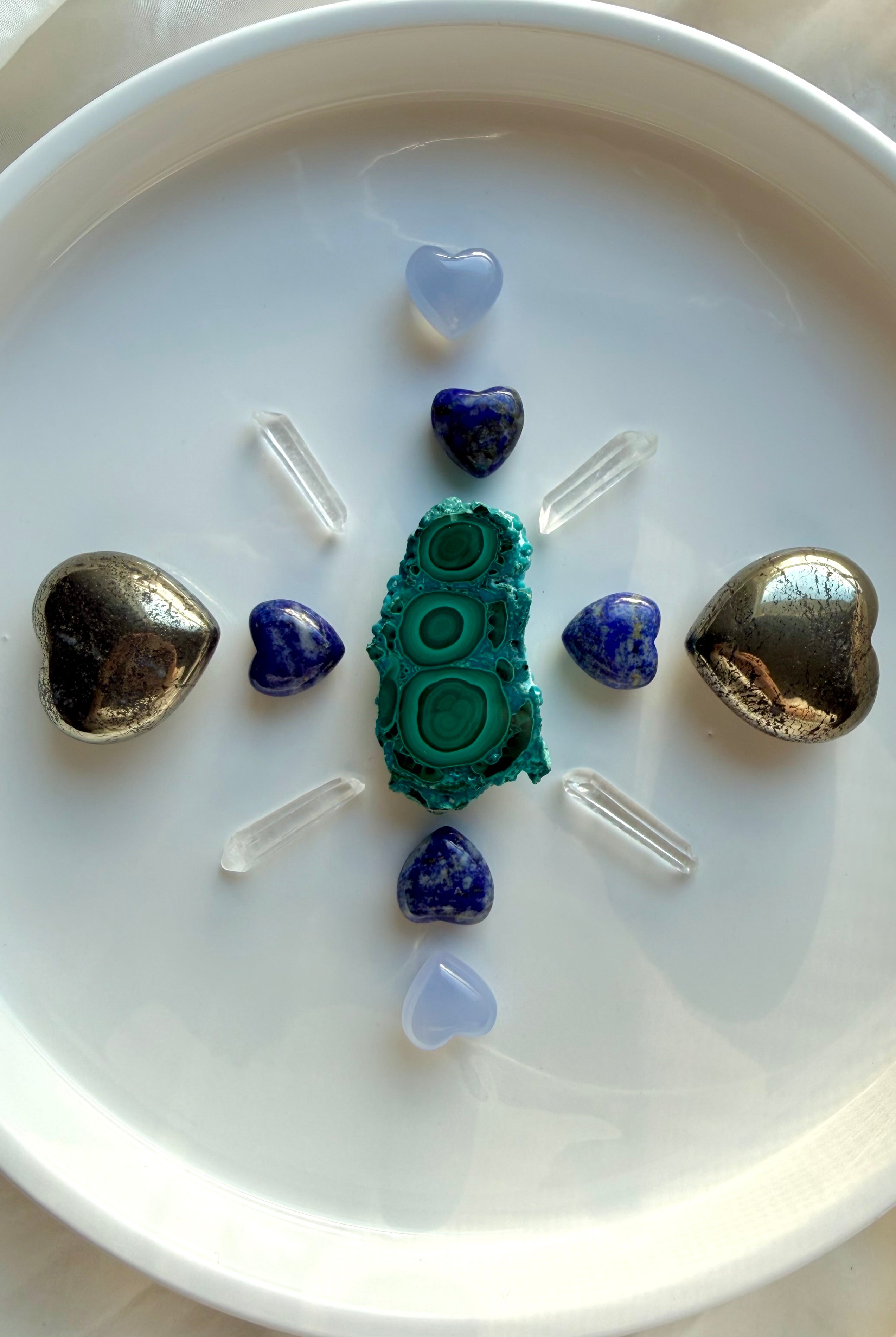 Crystal grid with pyrite hearts, lapis lazuli hearts, blue chalcedony hearts, malachite centerpiece, and clear quartz points arranged for balance, intention setting, and chakra alignment