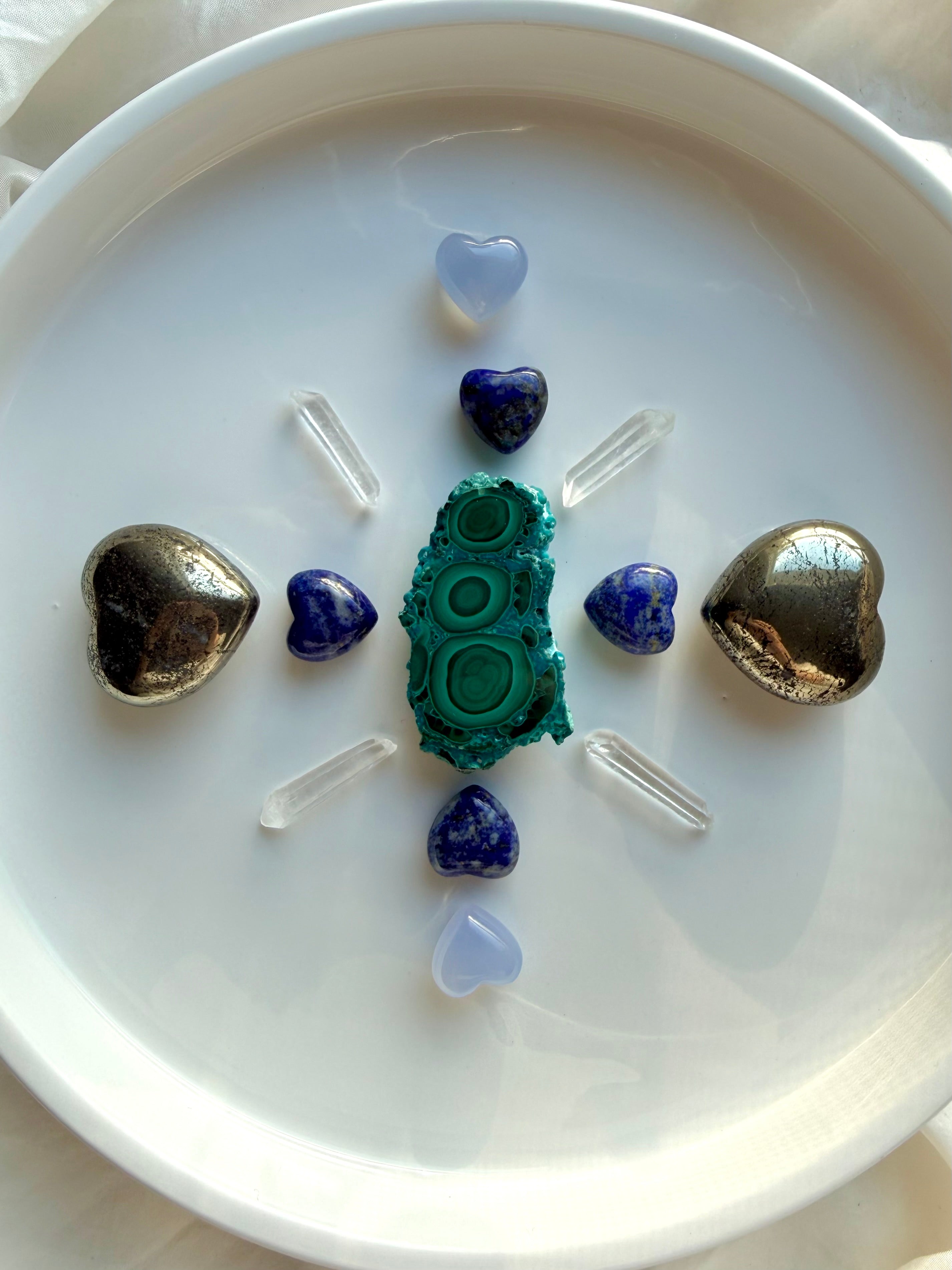 Crystal grid with pyrite hearts, lapis lazuli hearts, blue chalcedony hearts, malachite centerpiece, and clear quartz points arranged for balance, intention setting, and chakra alignment