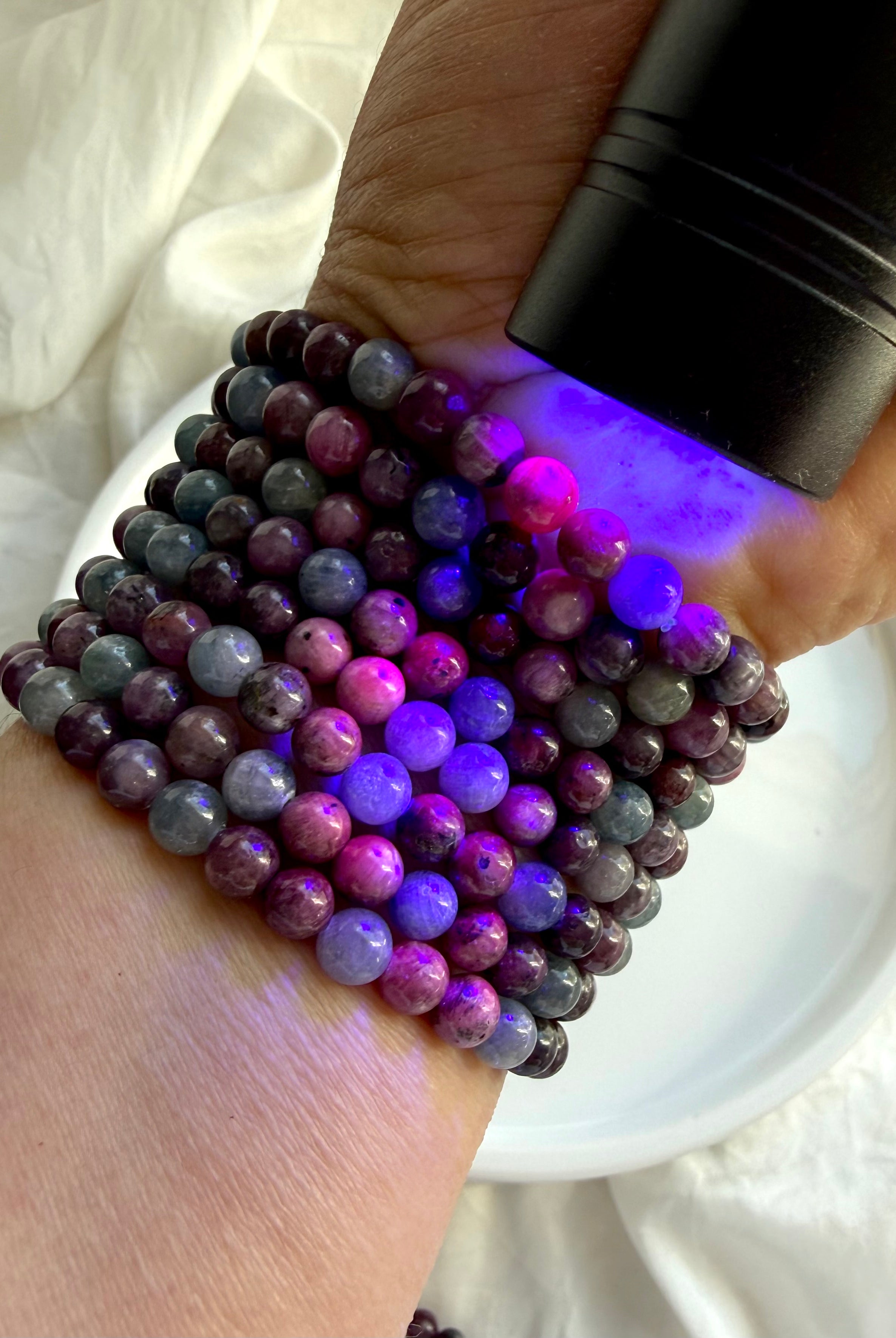 Ruby Sapphire bracelets under UV light revealing fluorescent ruby gemstones and natural sapphire beads