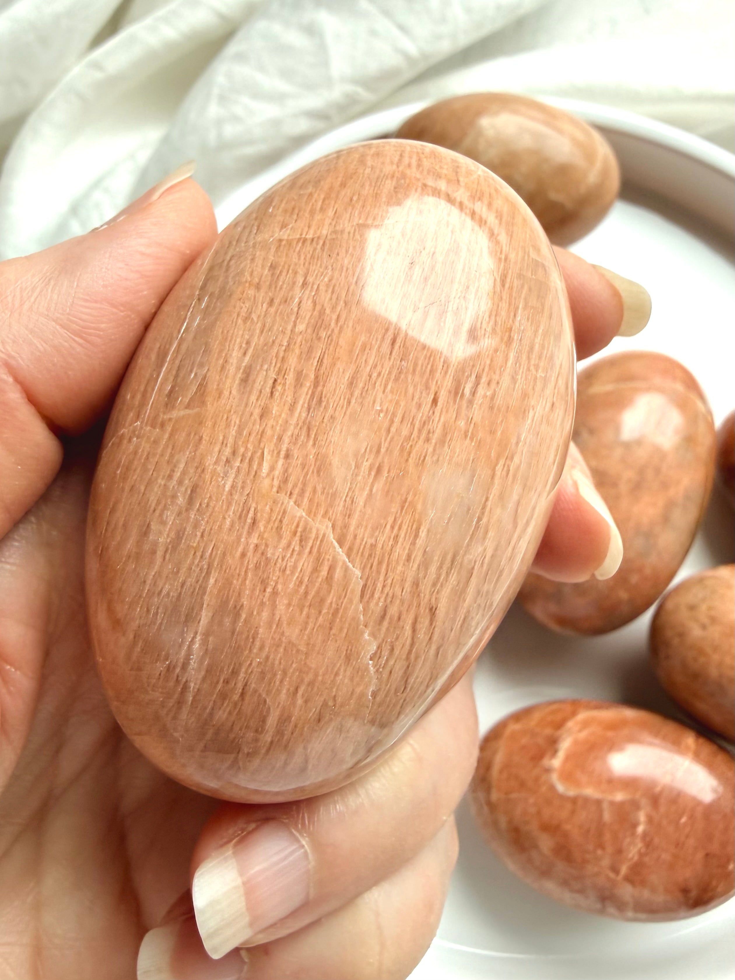 Collection of large Peach Moonstone palm stones with rounded polished oval shapes and natural color variation