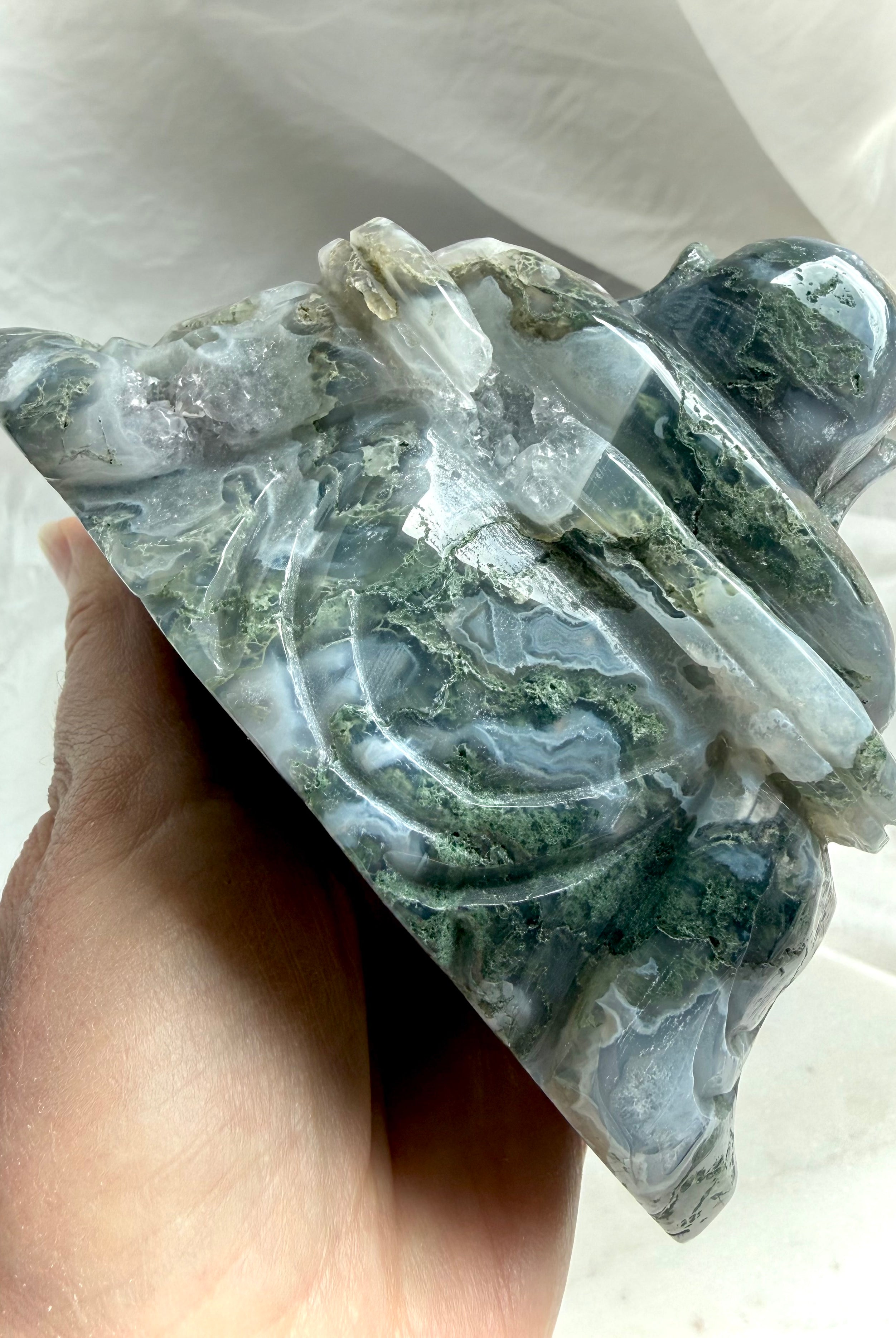 Back view of a Large Moss Agate Laughing Buddha statue showing scenic inclusions and carving detail