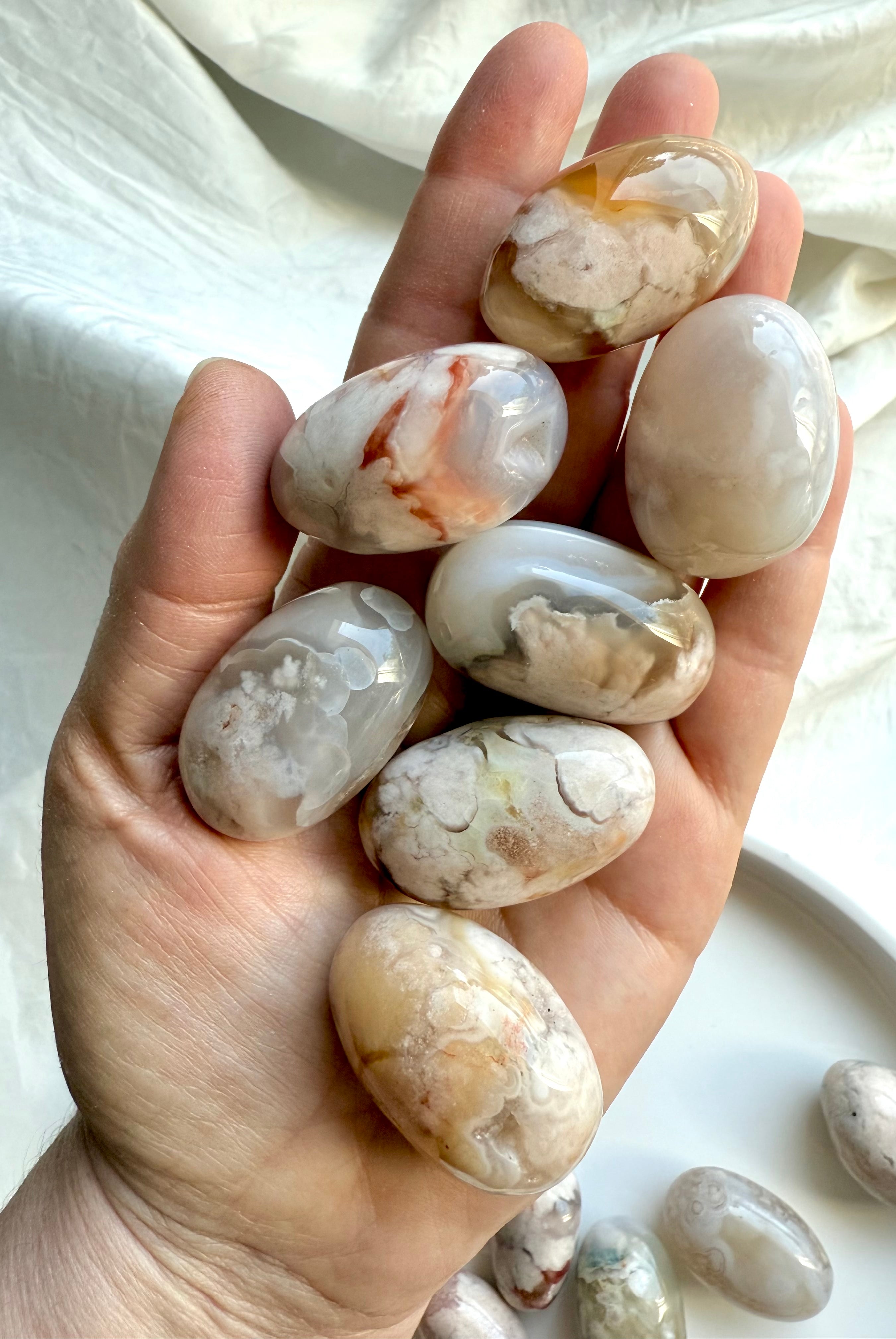 High quality Flower Agate tumbled stones with pastel color patterns shown on a hand for scale