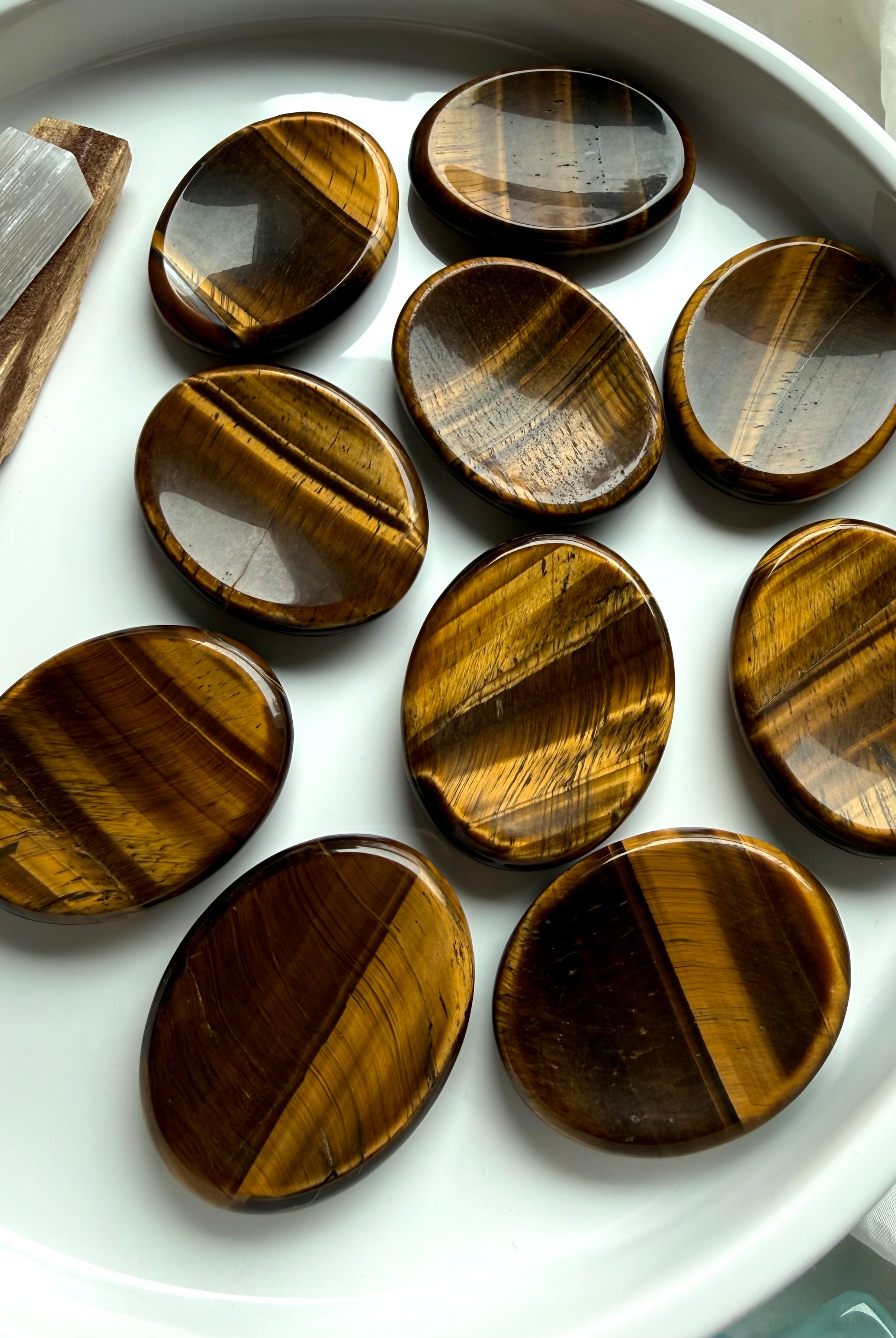 group of tiger’s eye worry stones scattered on marble surface, polished crystals for grounding stability and energy protection