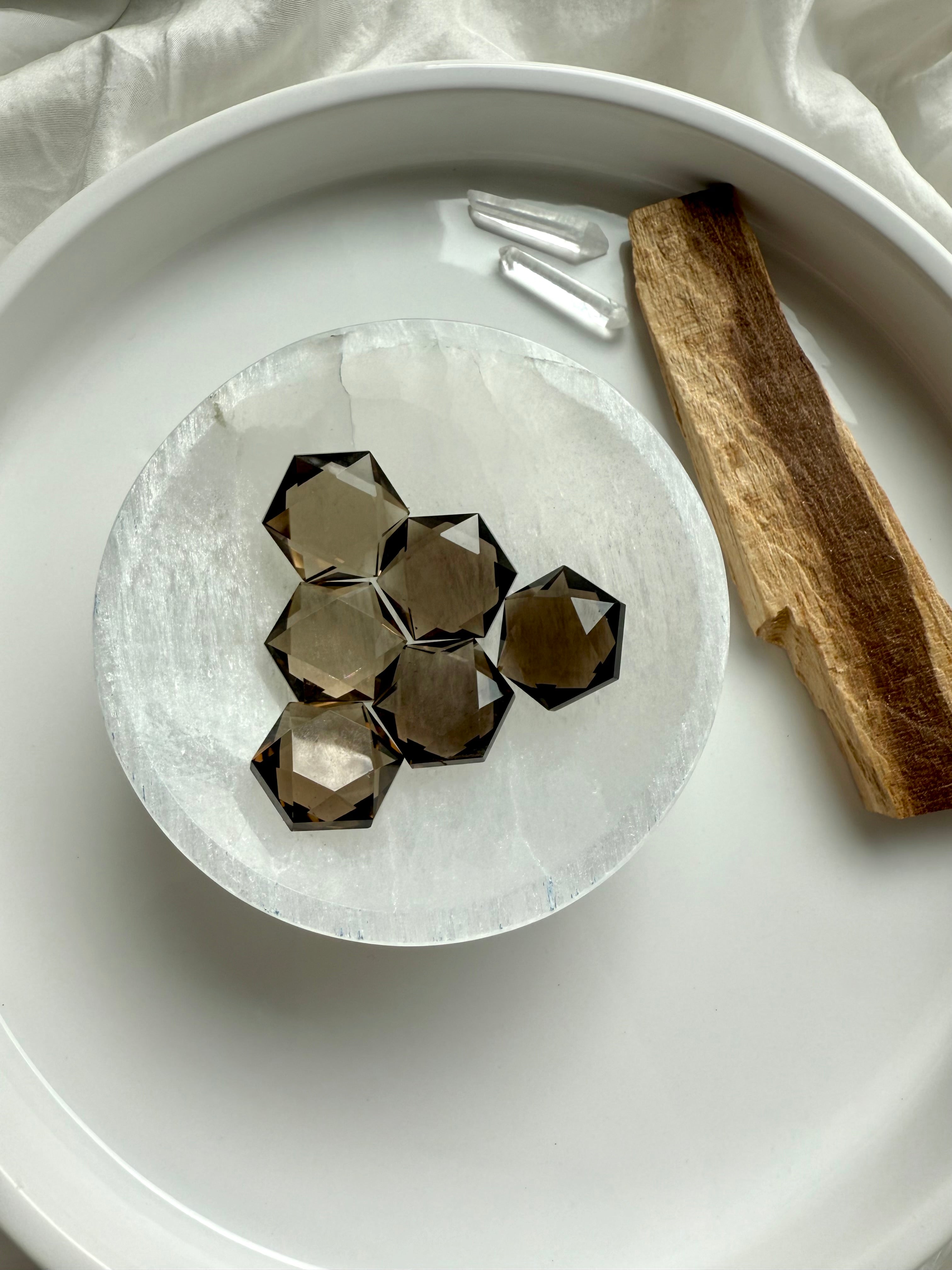 Faceted Smoky Quartz hexagon crystals with deep smoky brown color and precision-cut edges shown in a selenite bowl