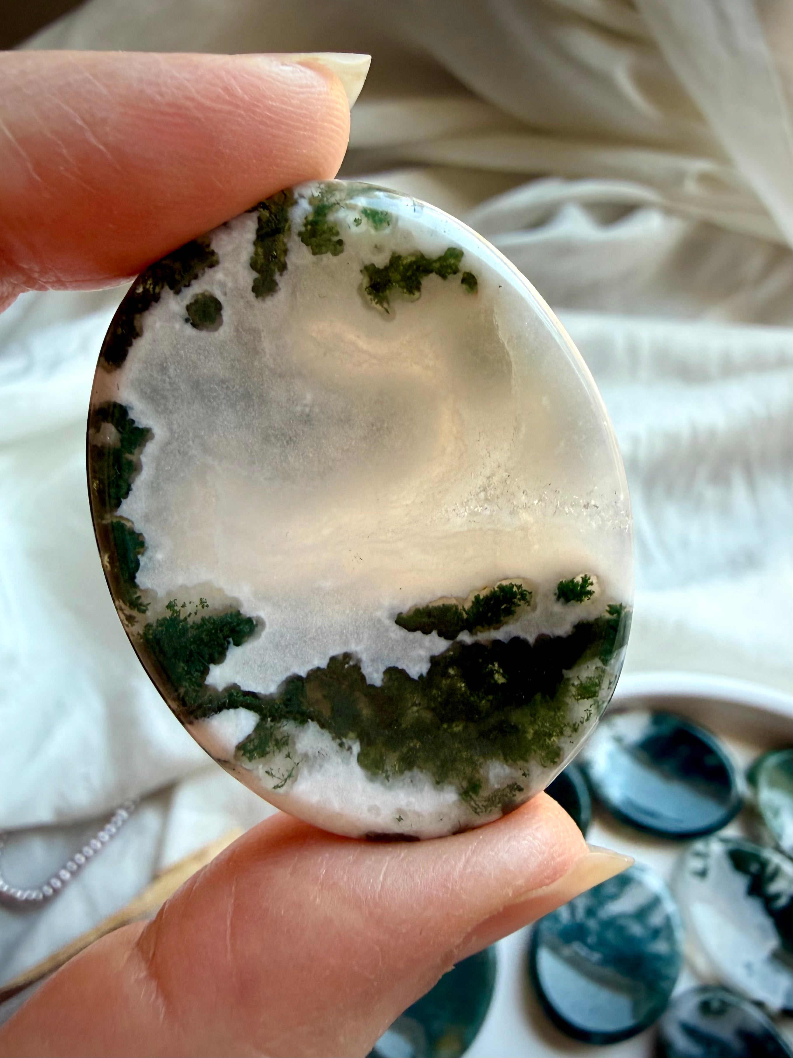 Polished Moss Agate oval thumb stones showing natural variation in green inclusions and clear quartz