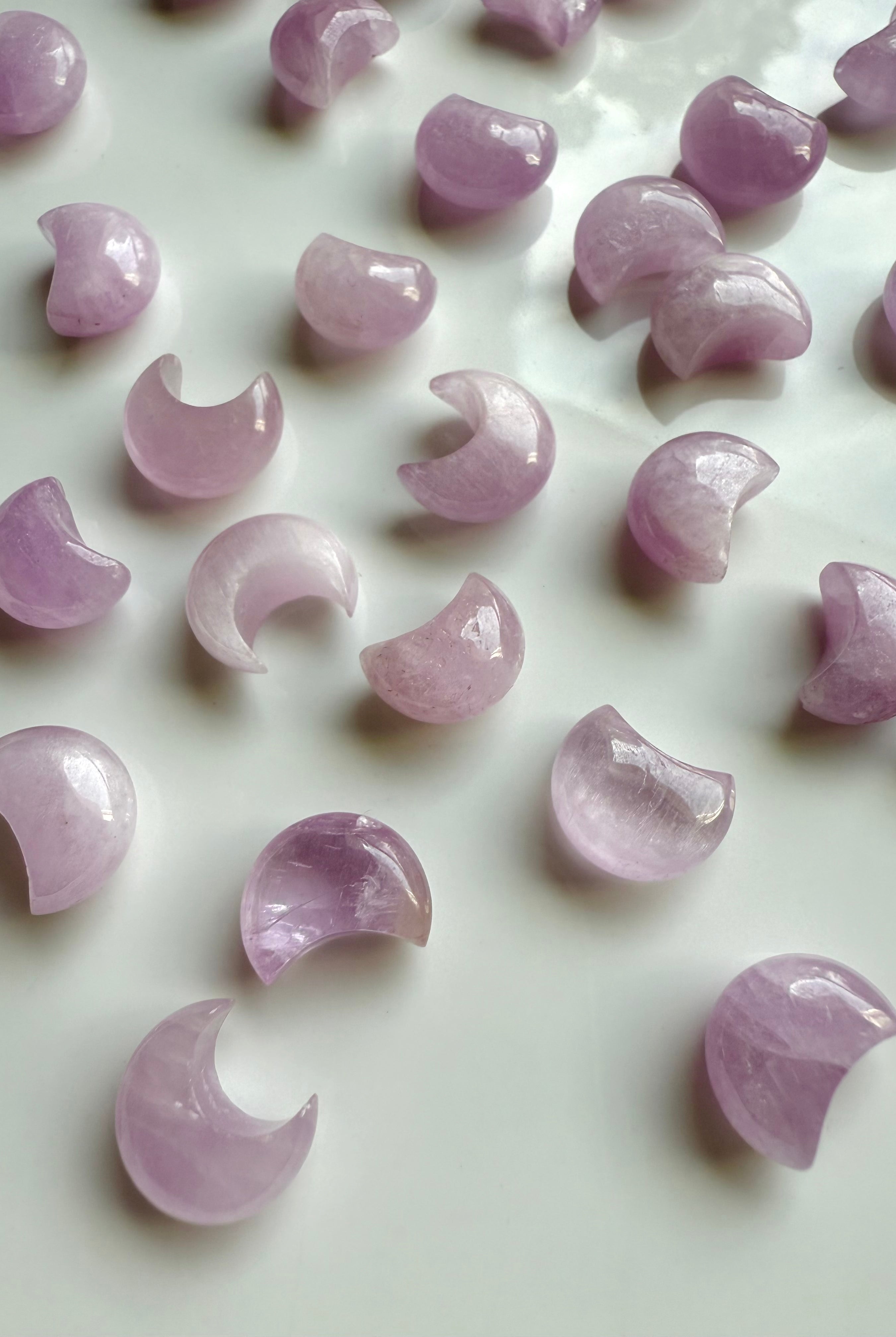 Mini Pink Kunzite crescent moons on a white plate — gentle pink crystal carvings for emotional healing & heart-centered energy work.