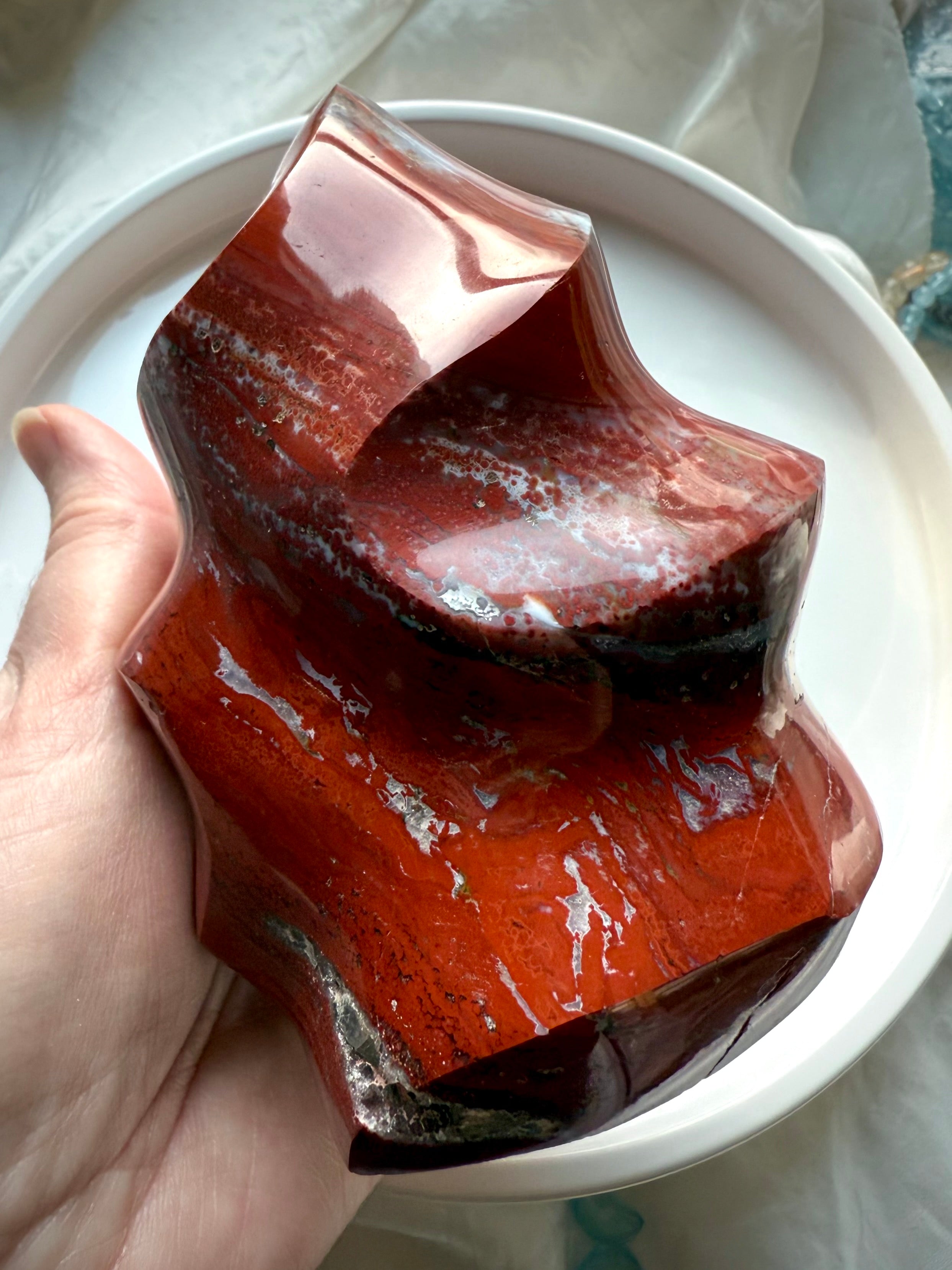 Polished Red Ocean Jasper flame carving with rich red hues, subtle orbs, and grounding crystal patterns.