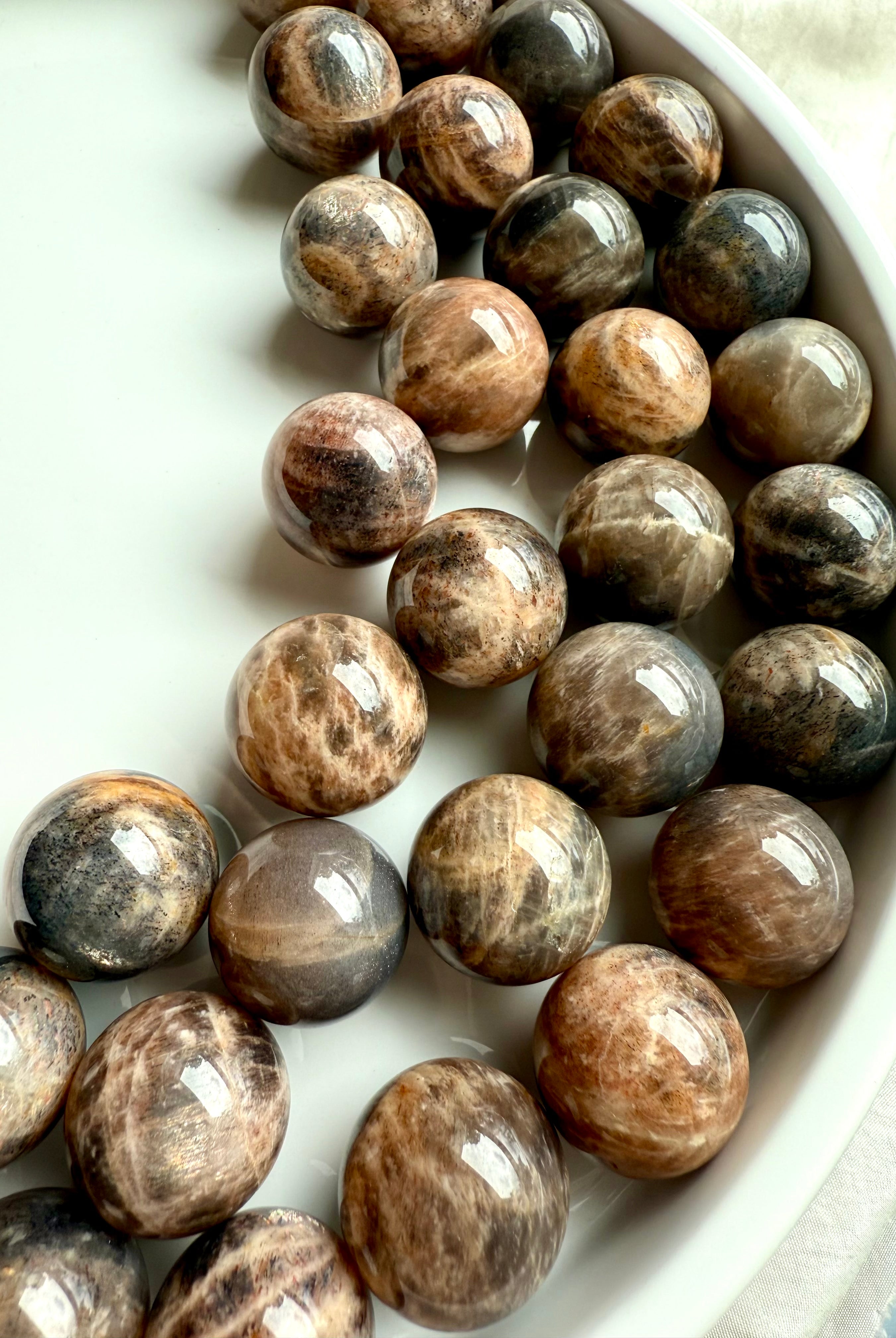 An array of Mini Black Moonstone spheres with golden chatoyant Sunstone flash and peachy tones