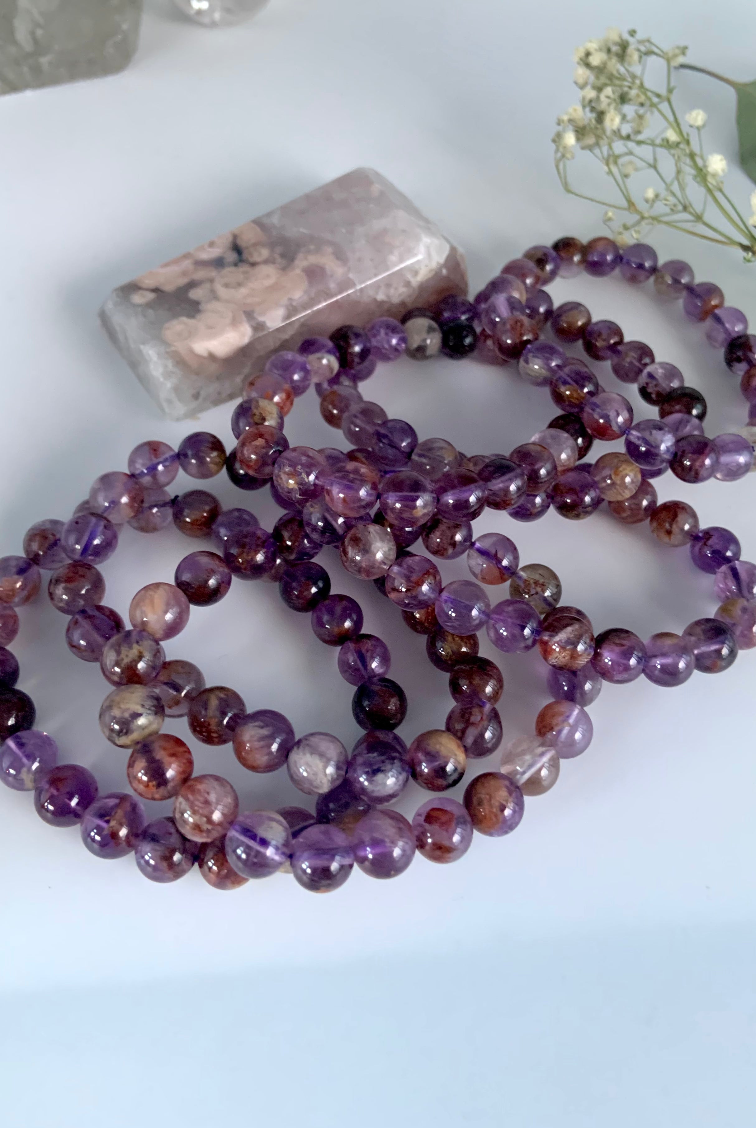 Stacked Super Seven bracelets in purple amethyst tones with natural mineral character