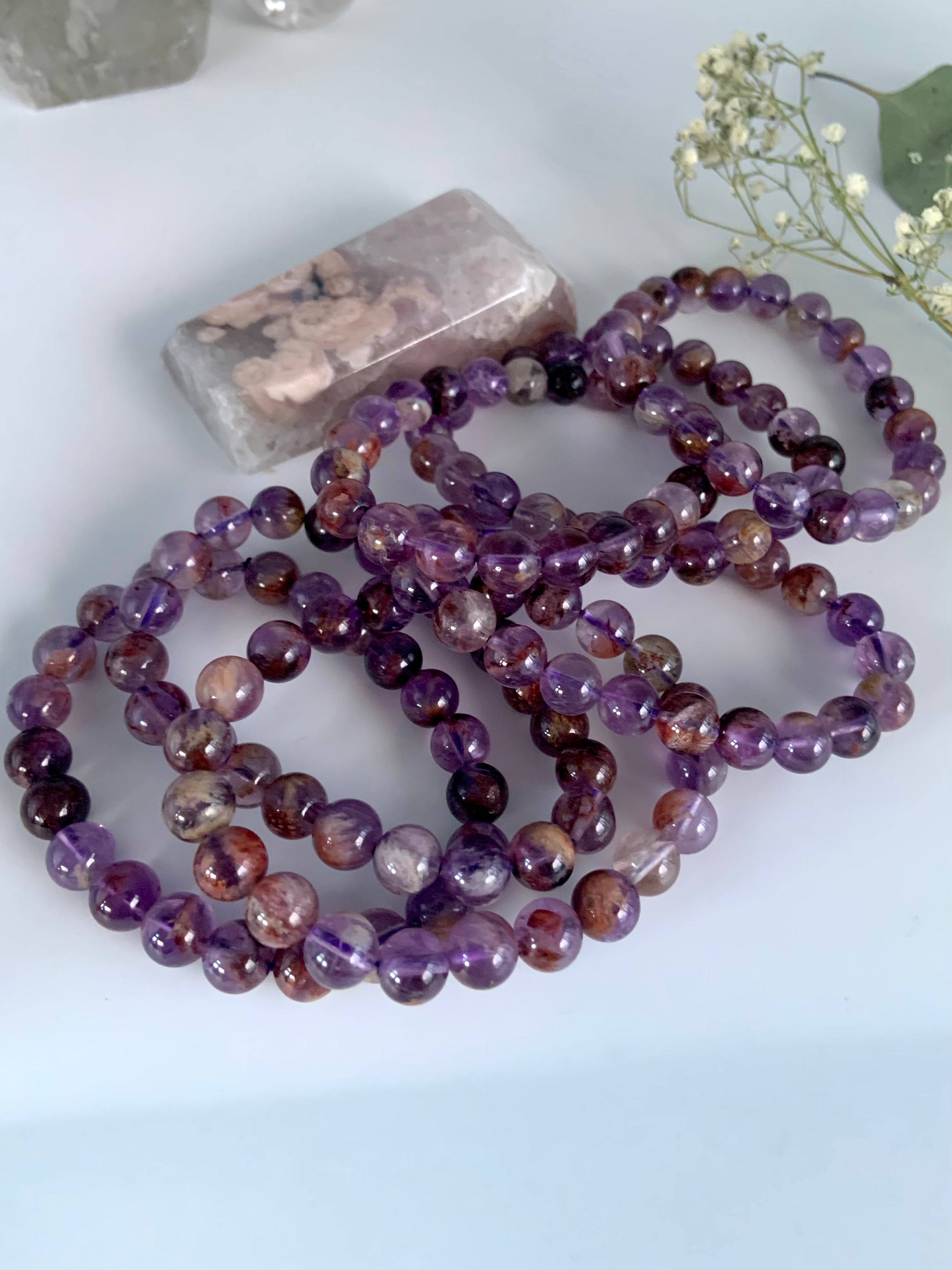Stacked Super Seven bracelets in purple amethyst tones with natural mineral character