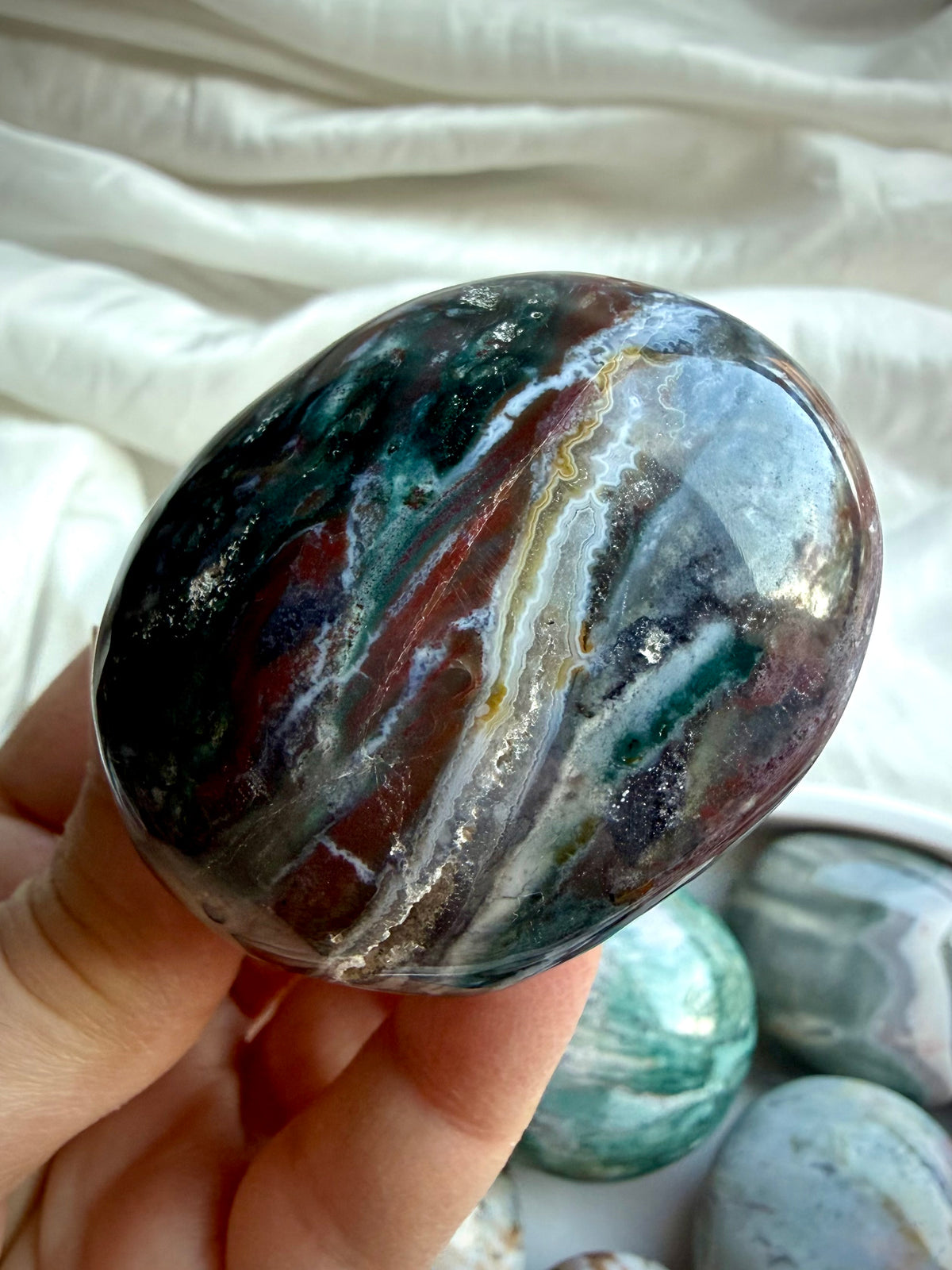 Ocean Jasper palm stone with dark green, rust, cream, and gray agate banding and distinctive mineral patterns