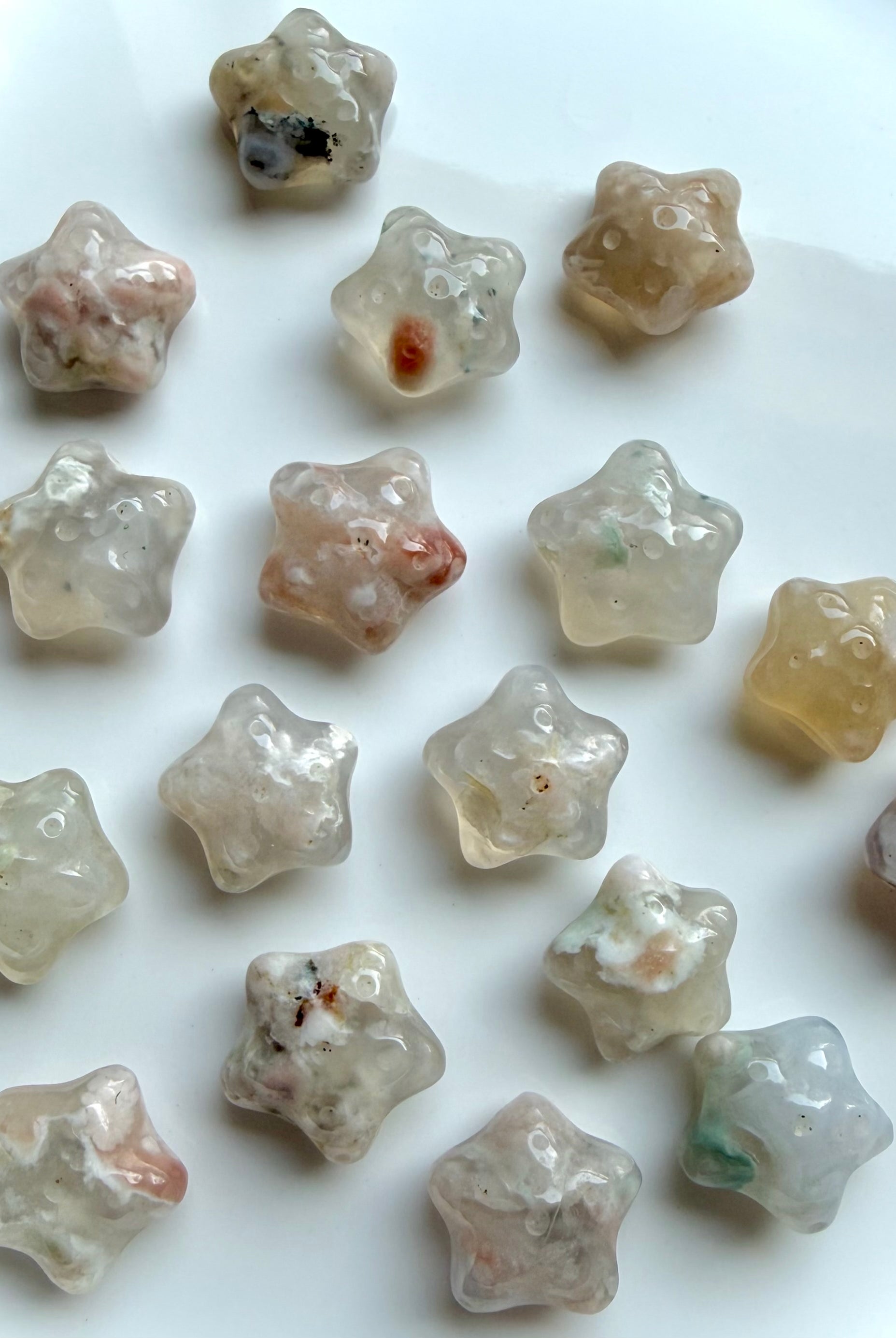 collection of mini Flower Agate starfish carvings arranged on plate with soft feminine colors and blossom patterns