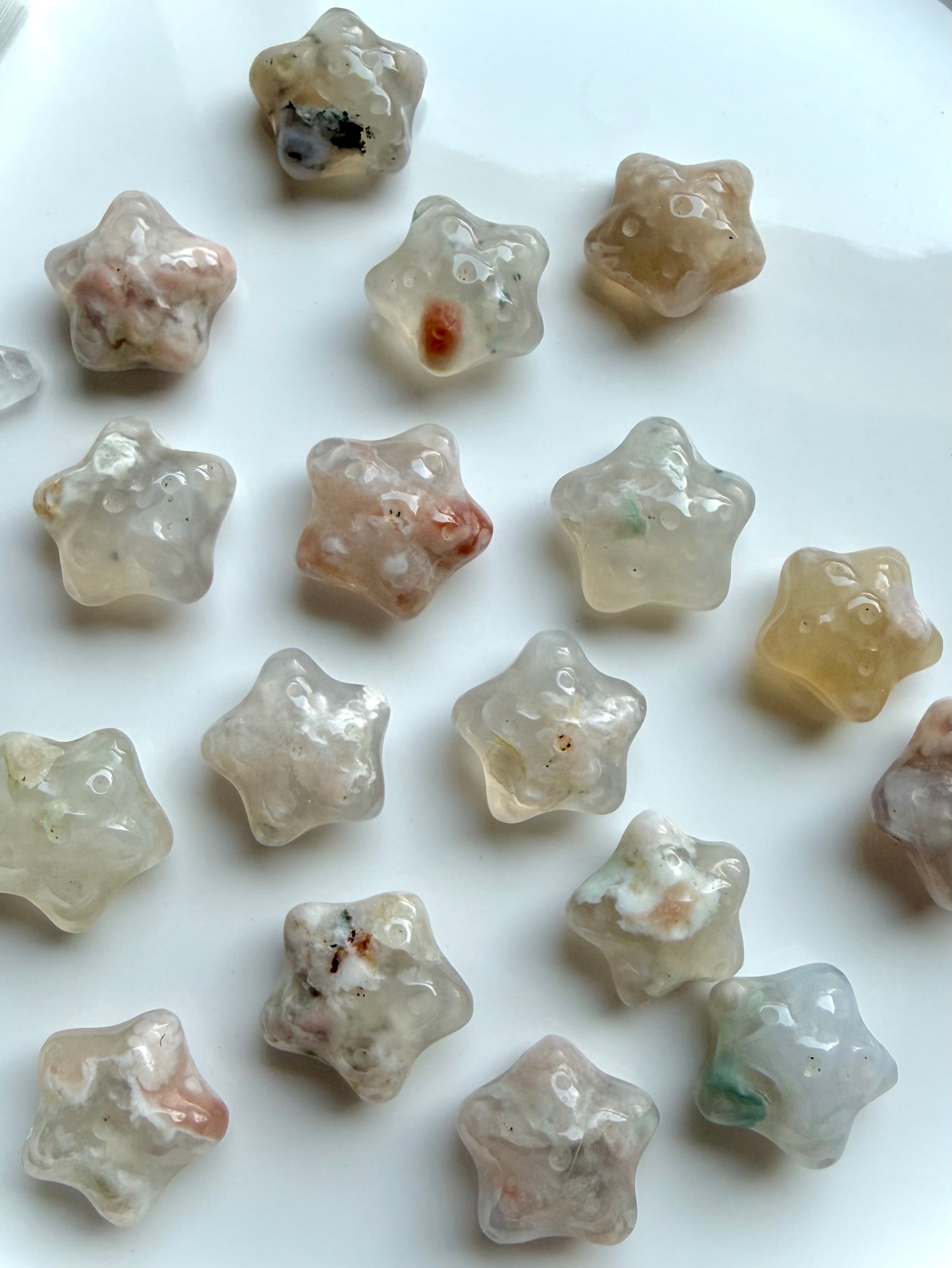 collection of mini Flower Agate starfish carvings arranged on plate with soft feminine colors and blossom patterns