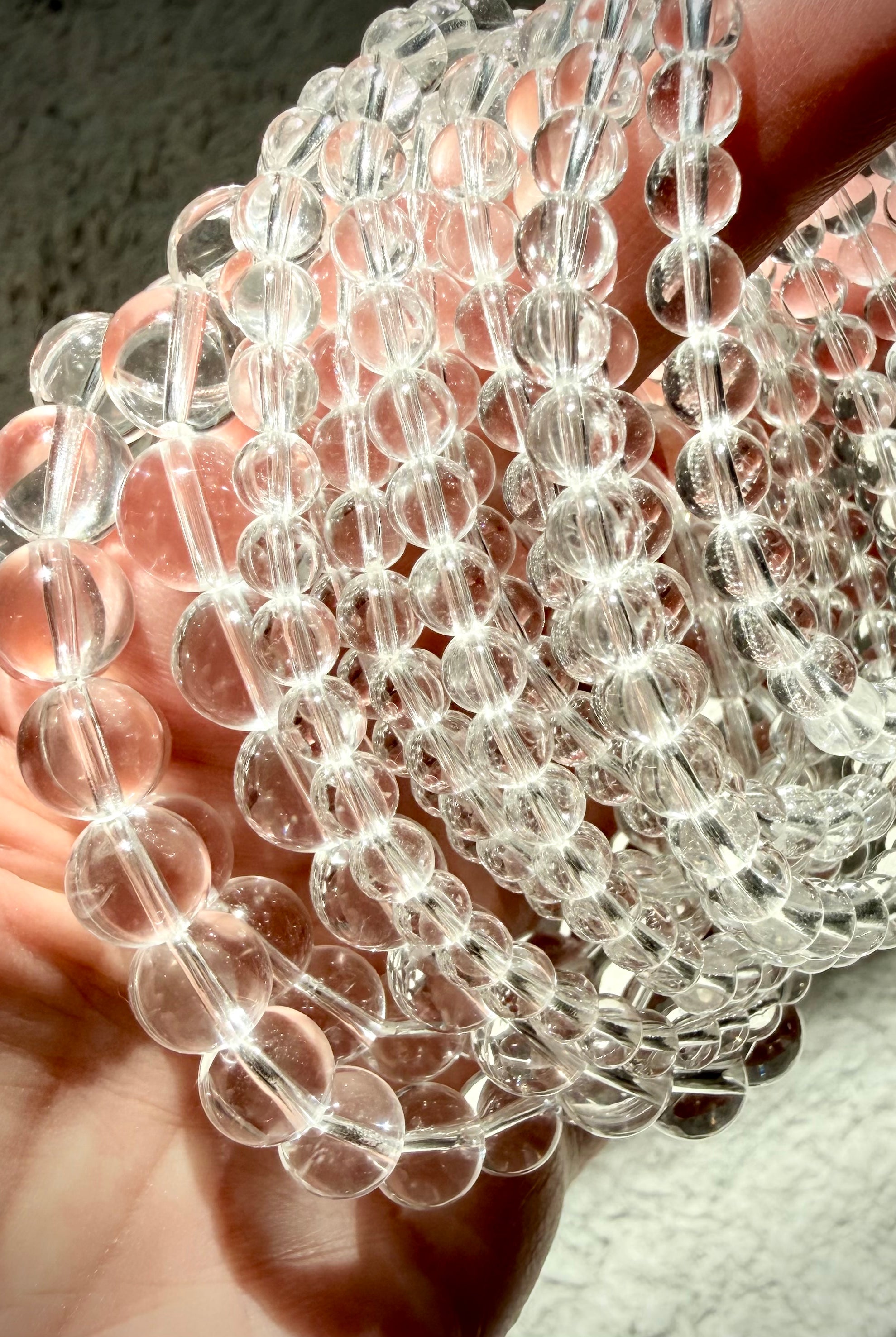 Clear Quartz bracelets arranged in a spiral showing multiple bead sizes and polished transparent crystal beads