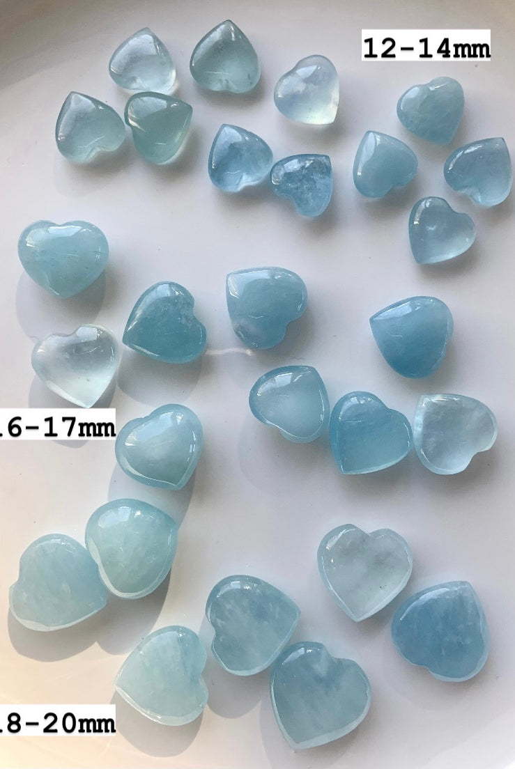 Aquamarine crystal hearts labeled with sizes 12–14mm, 16–17mm, 18–20mm — small gemstone hearts for throat chakra healing + peaceful communication.