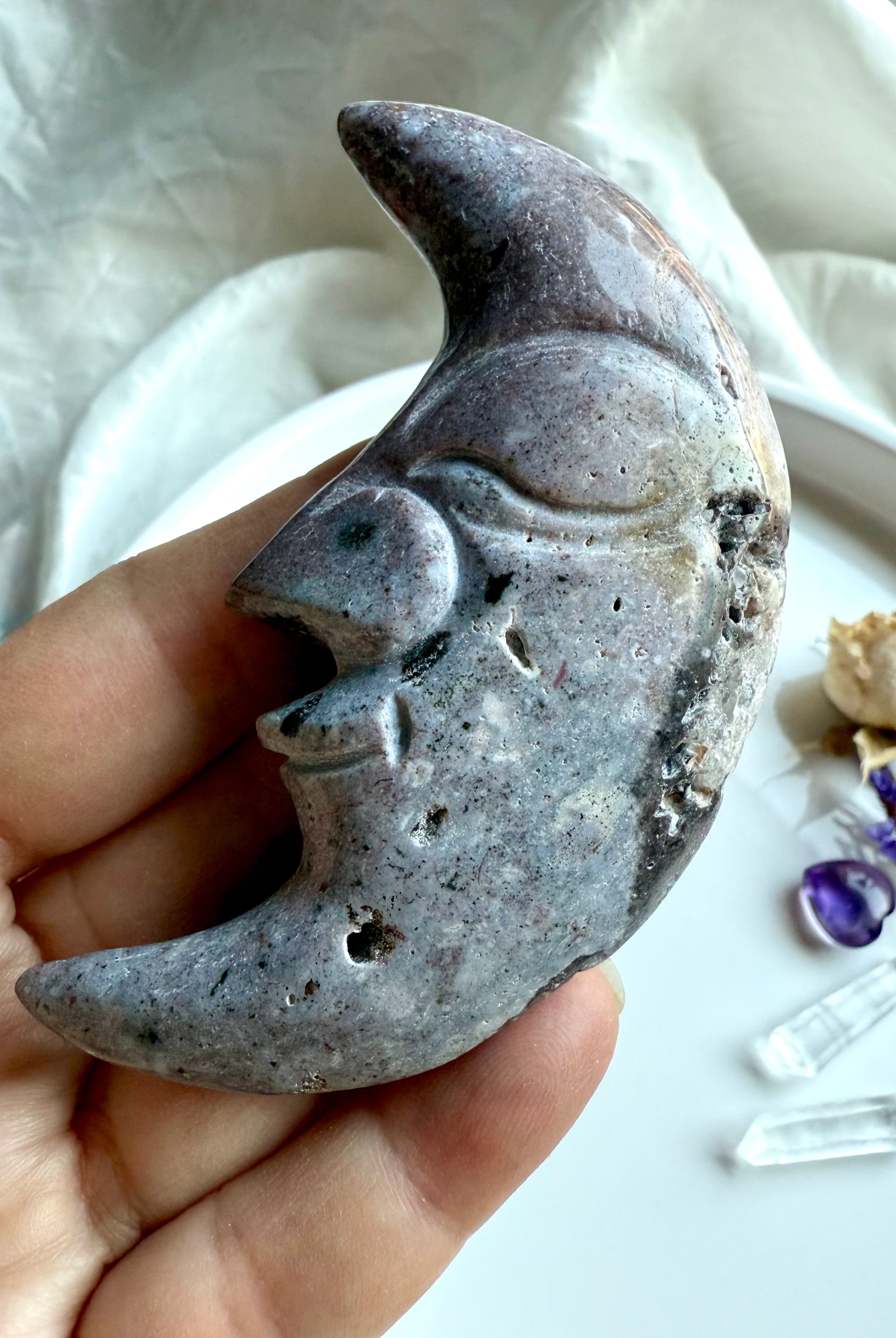 Purple Ocean Jasper moon face carving held in hand – crystal carving with unique banding and natural druzy details.