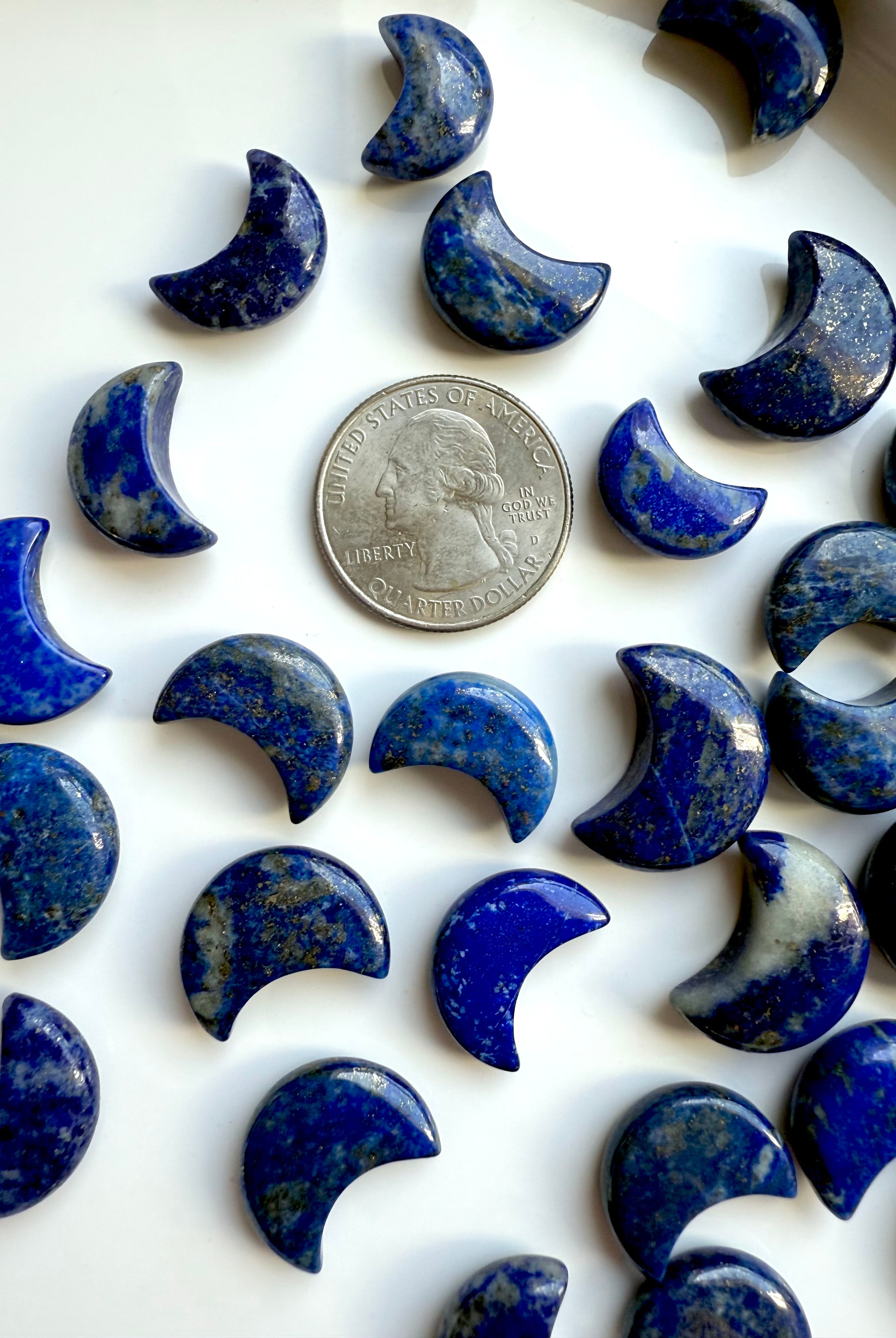 Mini Lapis Lazuli moon carvings next to a US quarter for size comparison