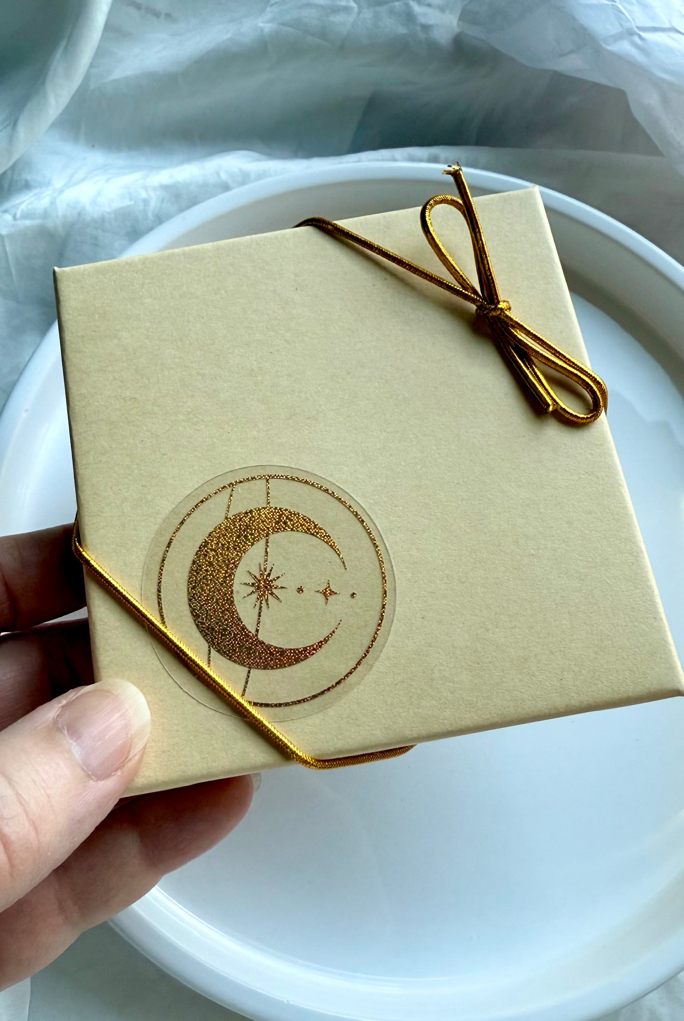 Gift box for Crystal Gifts tied with golden bow and celestial moon star sticker.