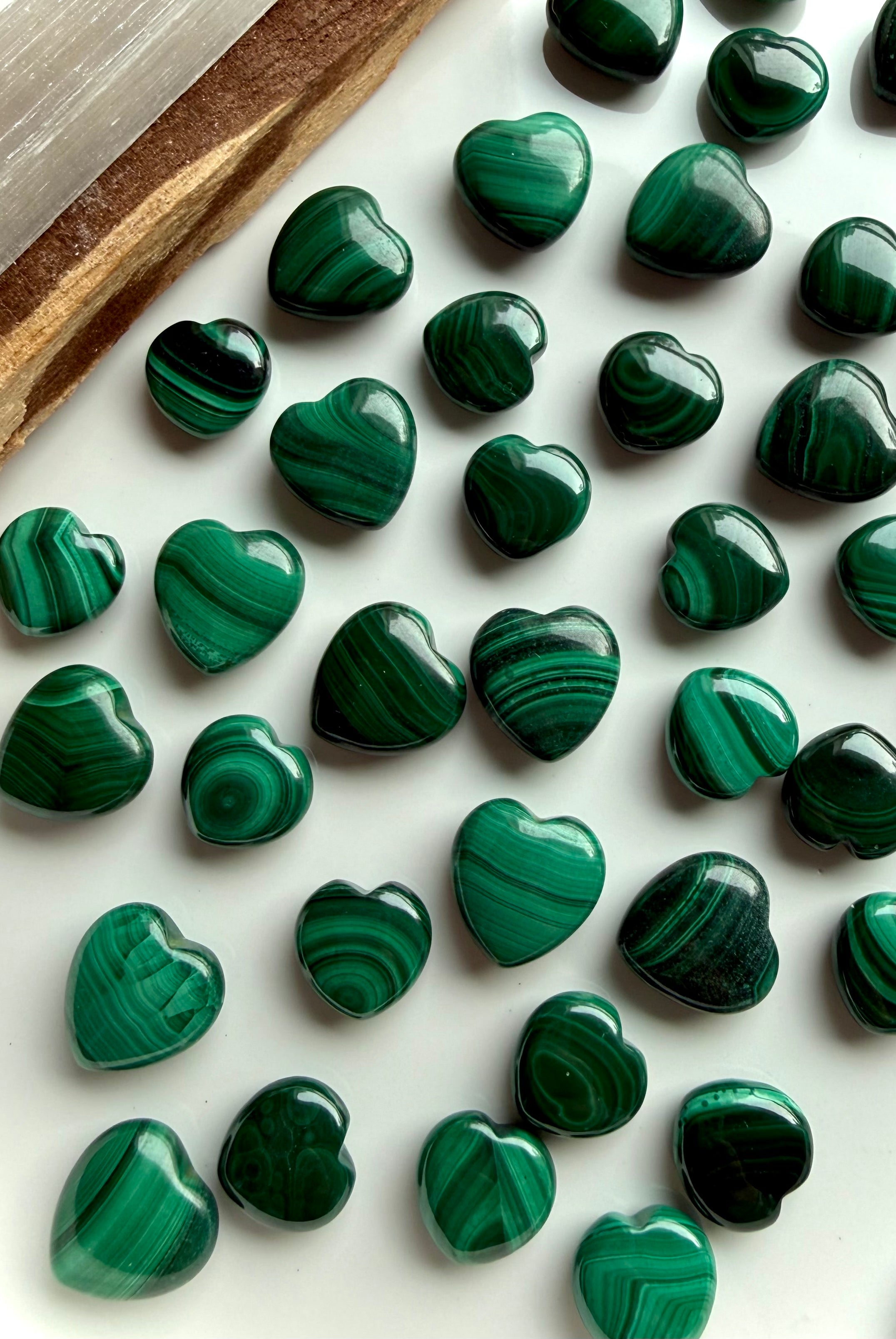 Mini Malachite crystal hearts arranged on a white plate with palo santo and selenite for sacred altar styling