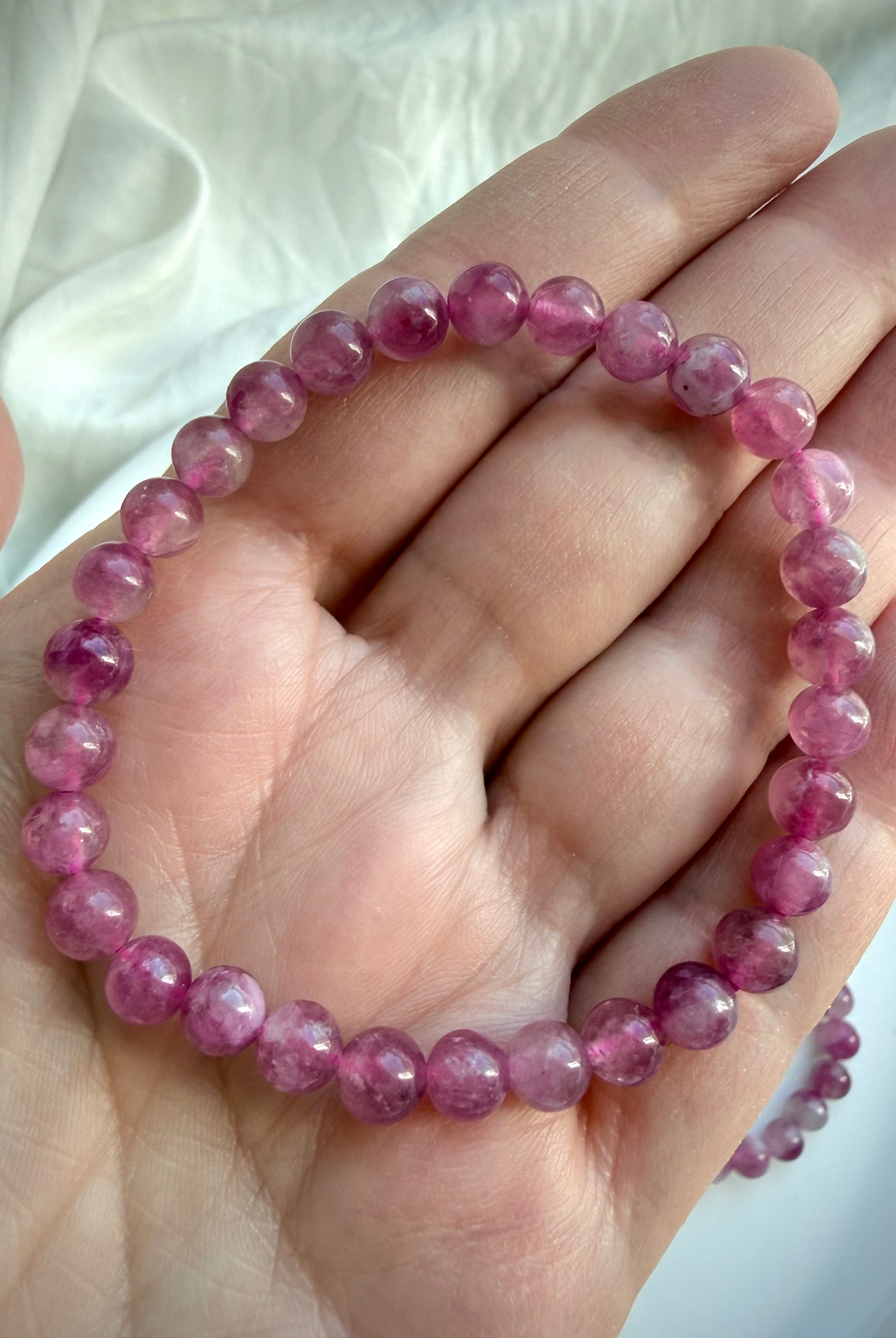 Single Pink Tourmaline bracelet with polished gemstone beads in soft blush and rich berry hues on an open hand