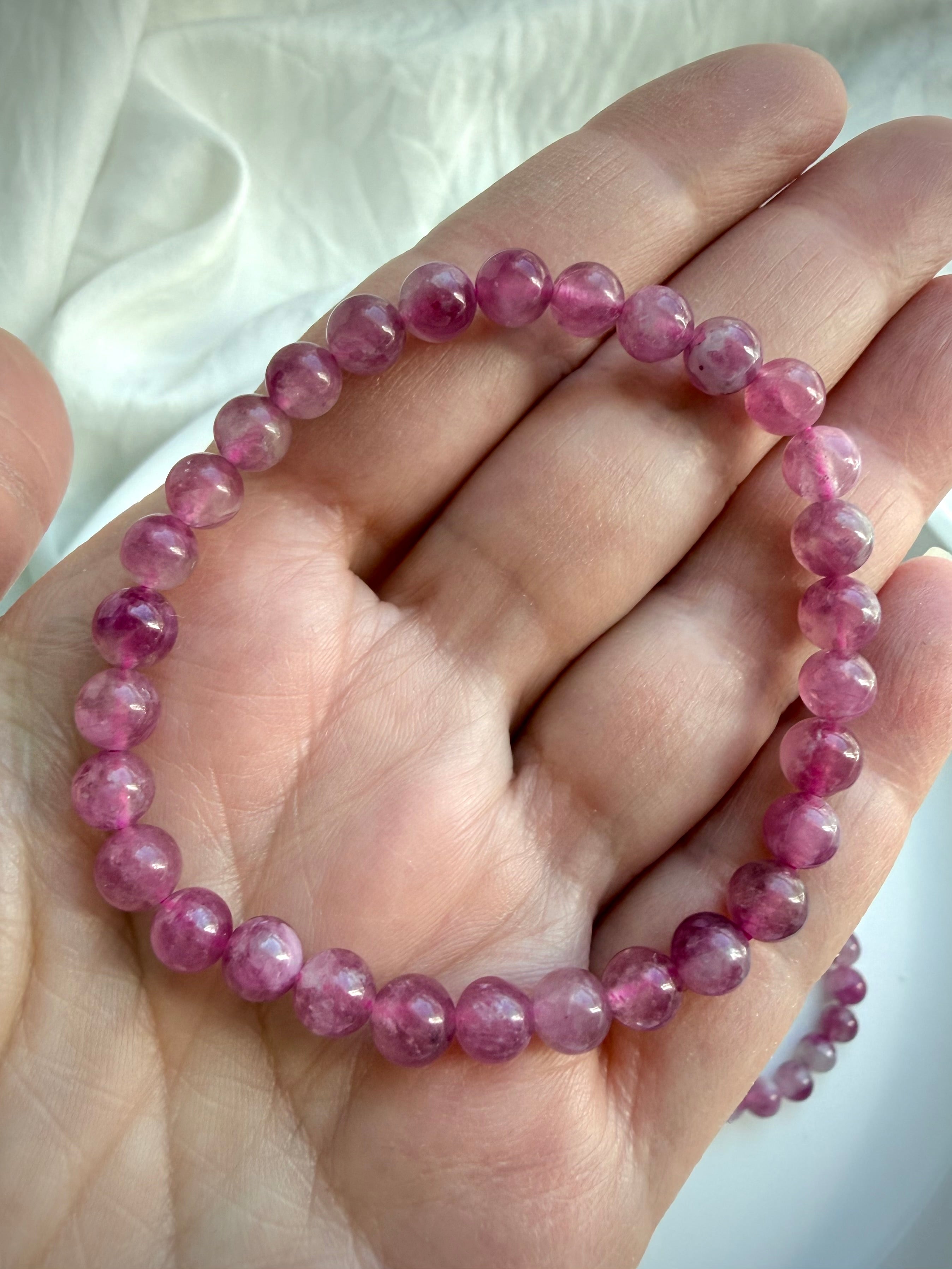 Single Pink Tourmaline bracelet with polished gemstone beads in soft blush and rich berry hues on an open hand
