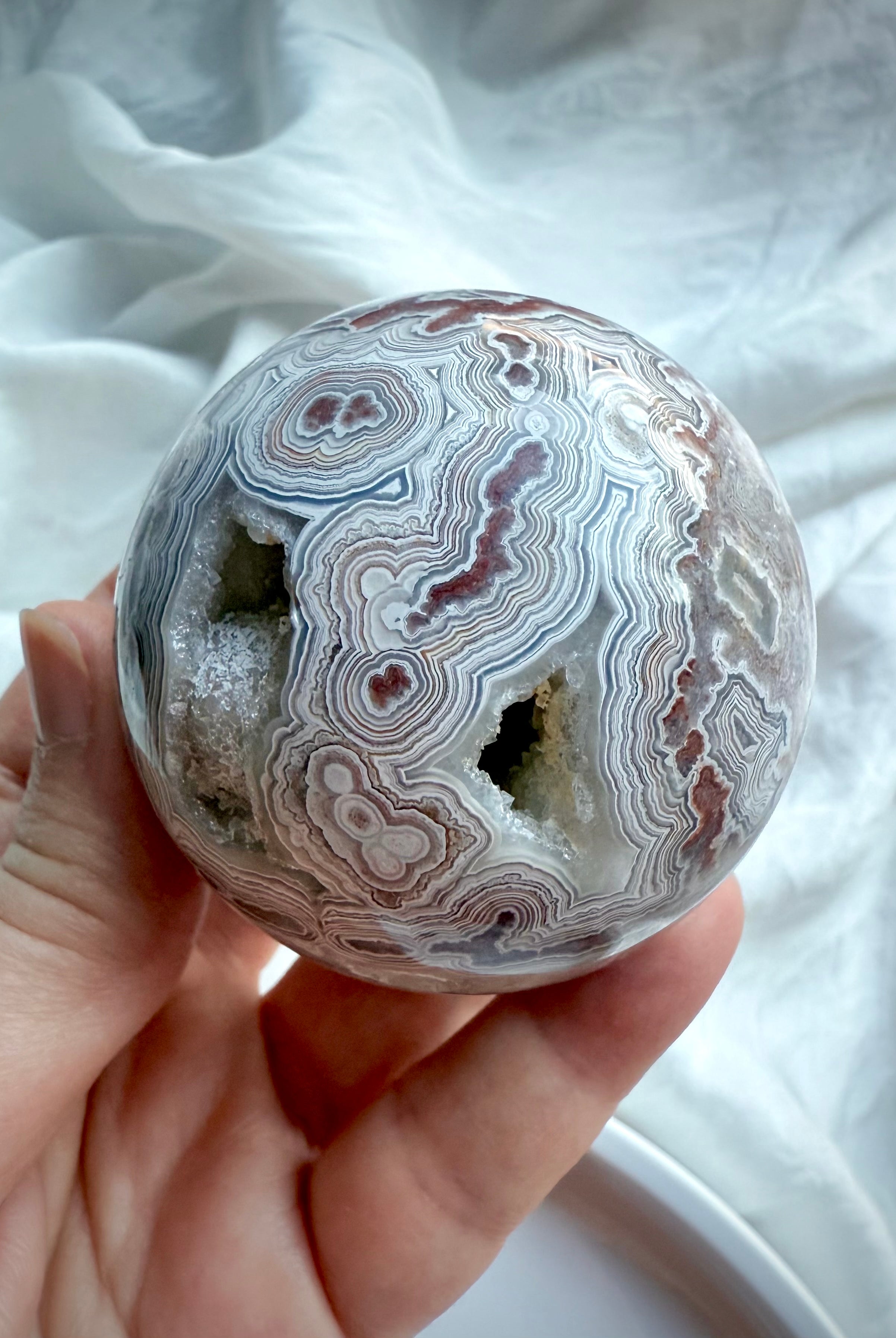 Root Chakra Crazy Lace Agate sphere with multiple geode windows, radiant pink quartz sparkle, and vibrant earth-tone patterning