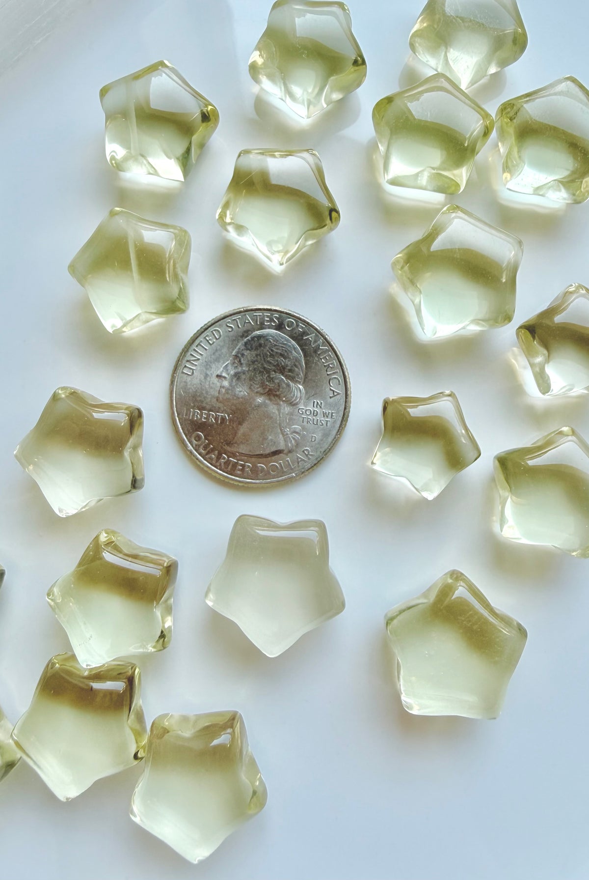 Mini Lemon Citrine stars shown with a US quarter to show their petite scale and golden-yellow color