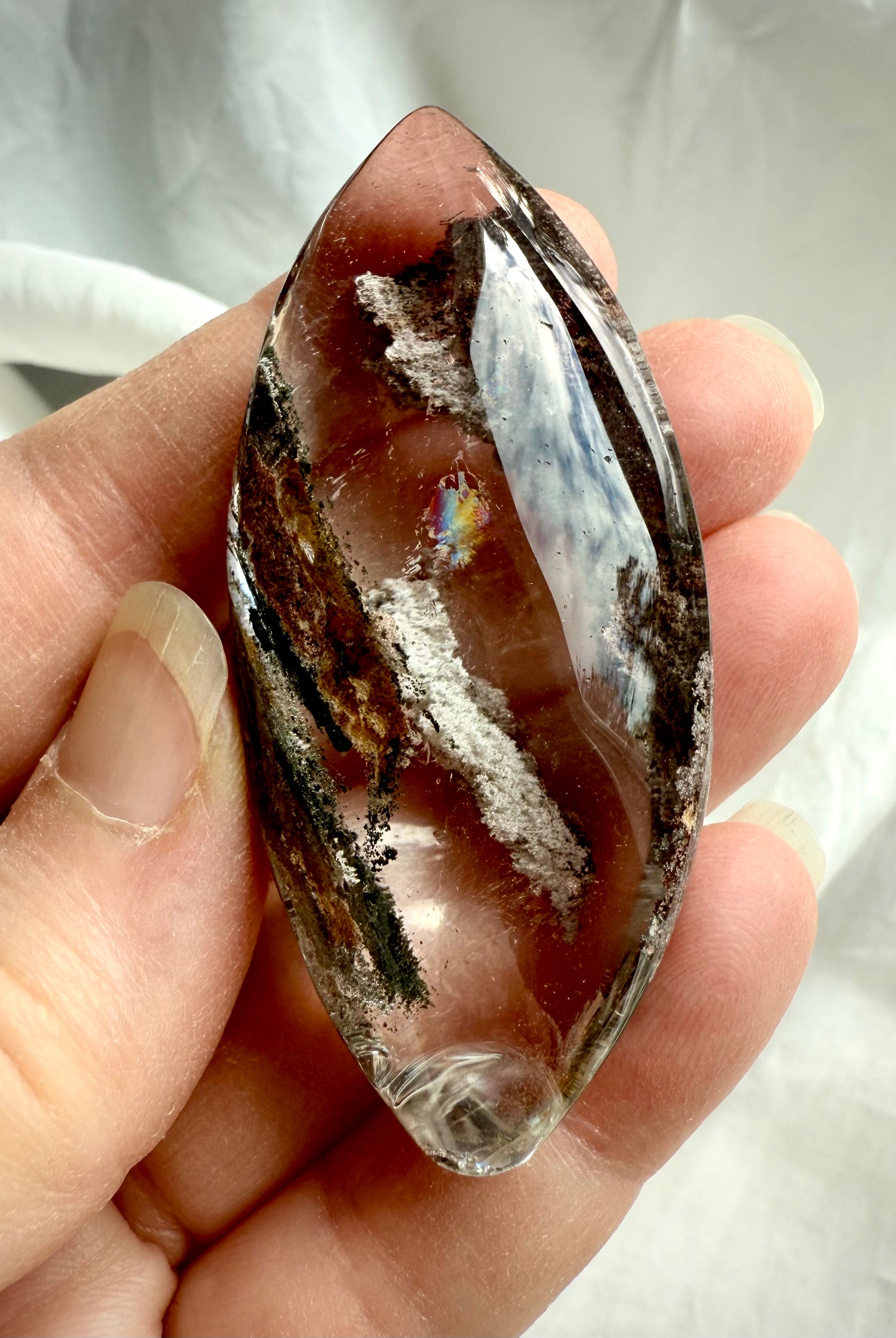 Garden Quartz marquise lens held in hand, showing scale, rainbows, and detailed phantom inclusions