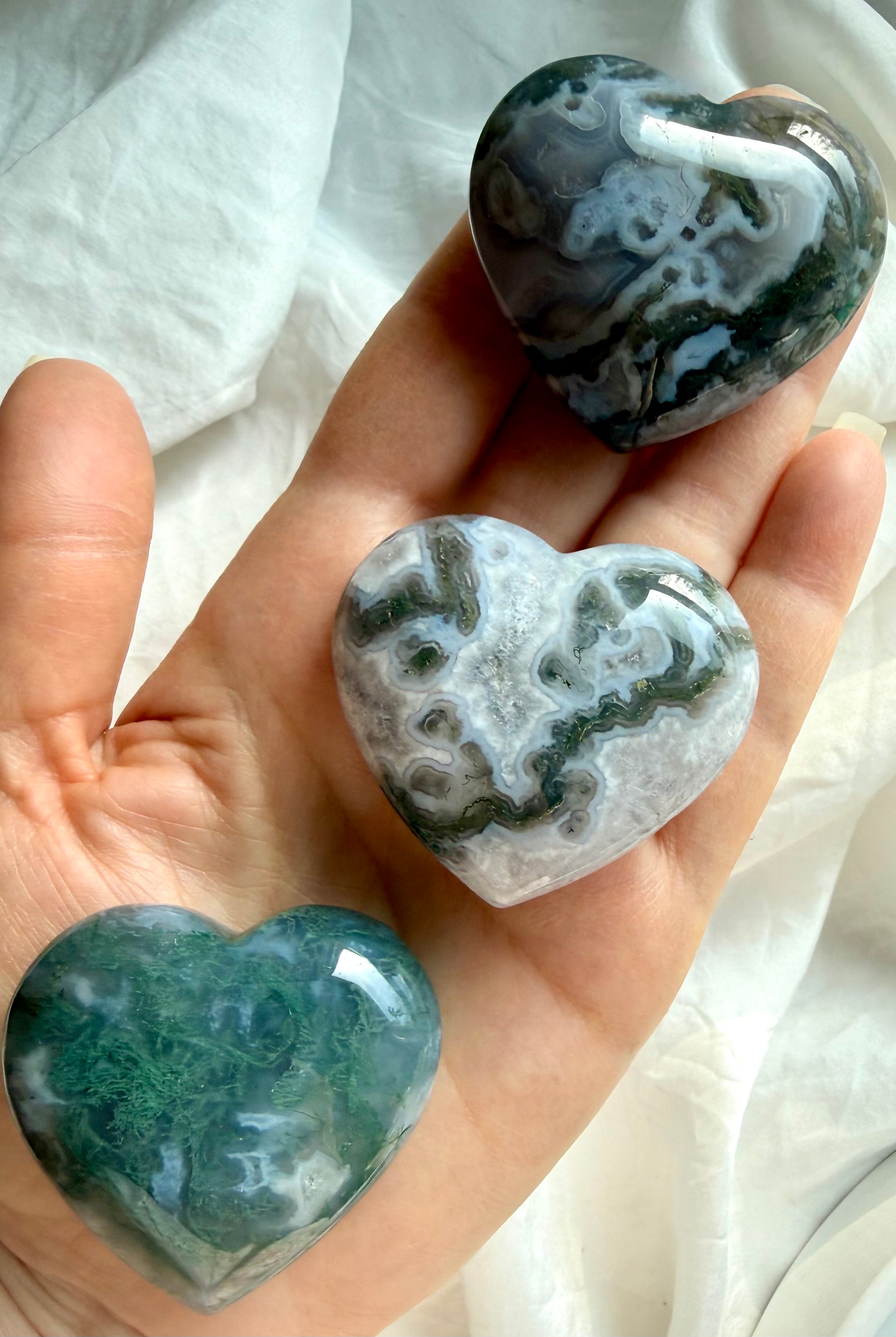 moss agate heart carving held in hand showing mossy green inclusions and natural chalcedony patterns