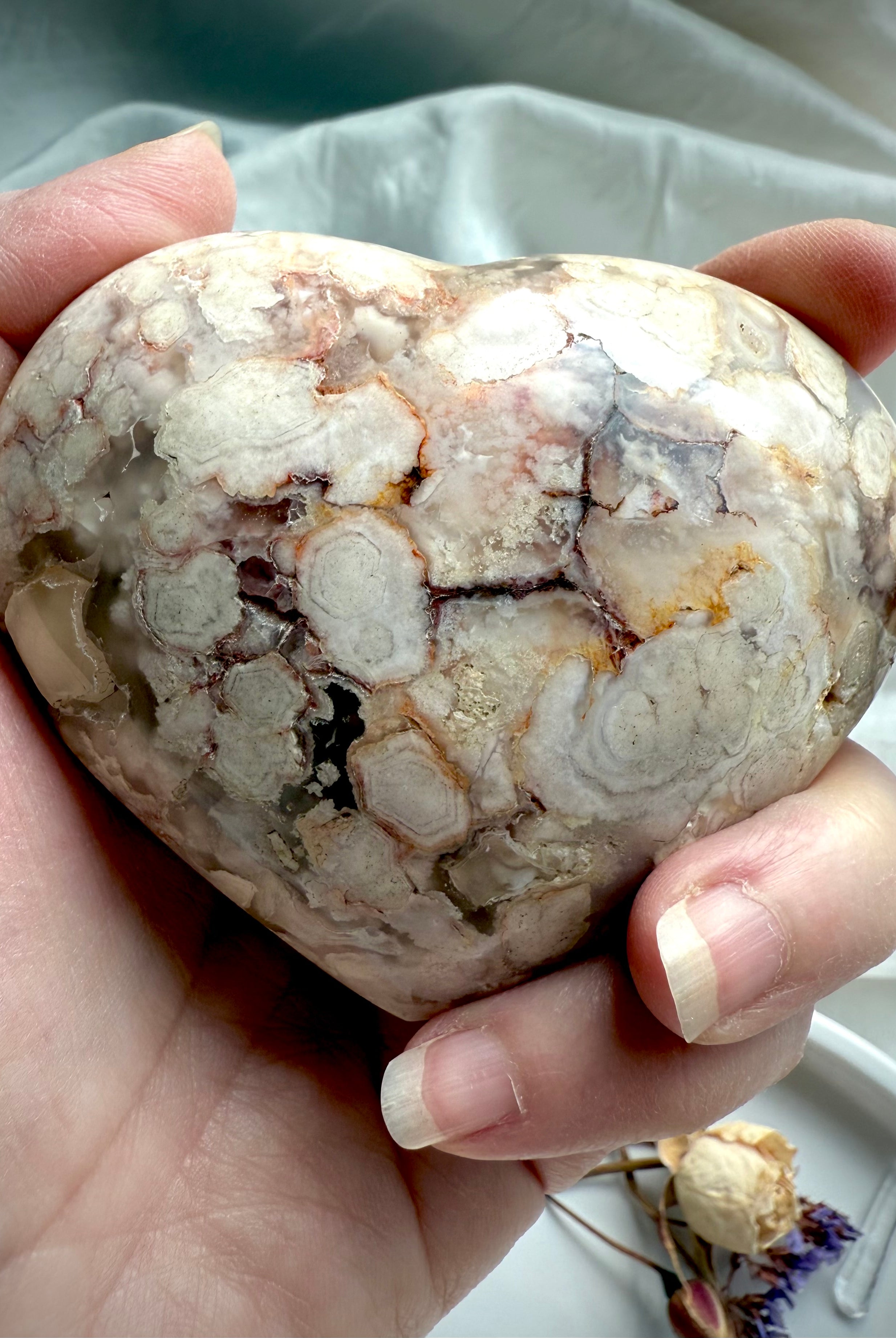 Flower Agate heart held in hand, highlighting its blooming chalcedony patterns and earthy pastel hues — supportive crystal for emotional balance, inner growth, and heart chakra healing.