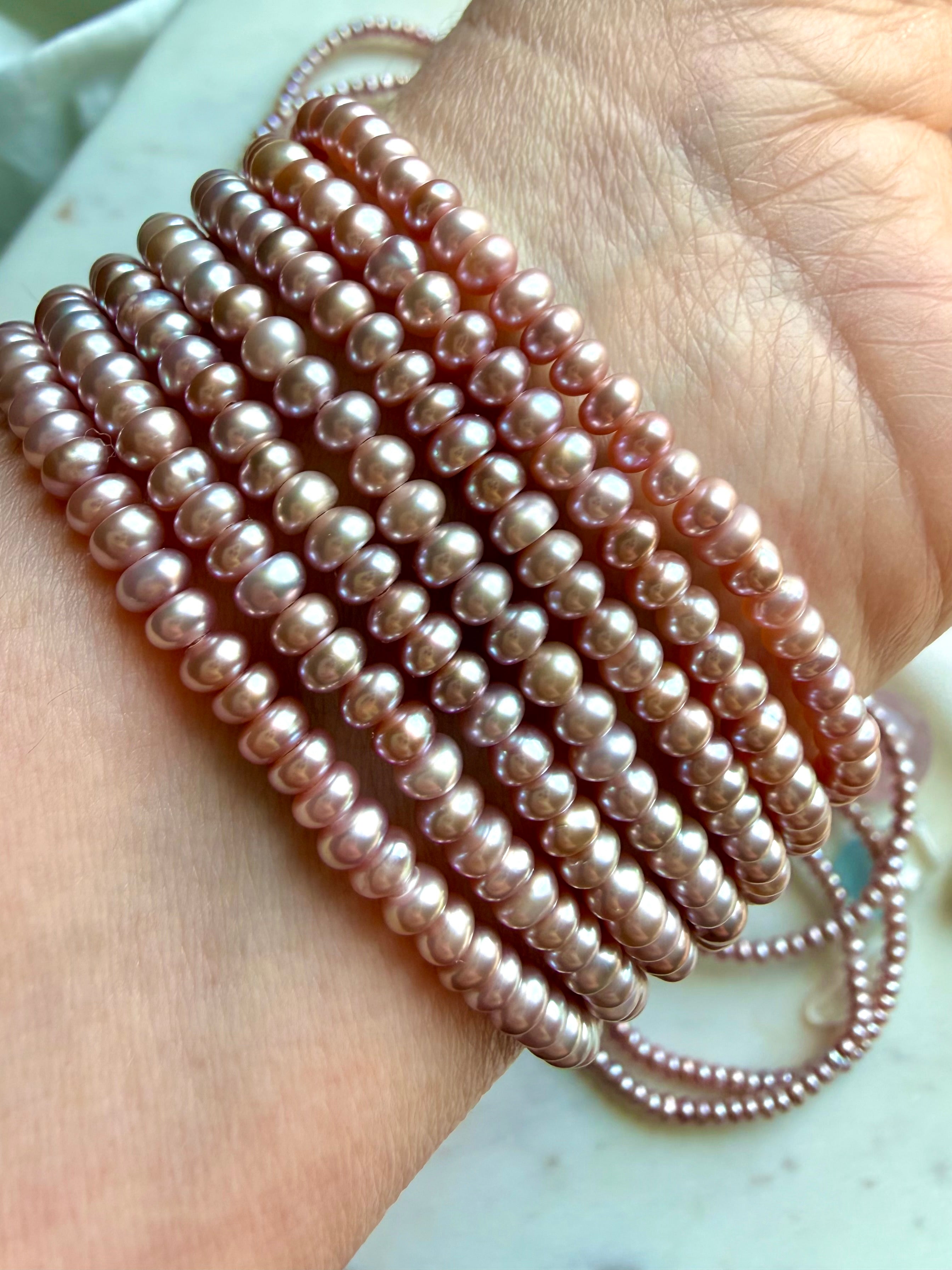 stacked pink freshwater pearl bracelets worn on wrist, elegant pearl bracelet layering for feminine energy and style