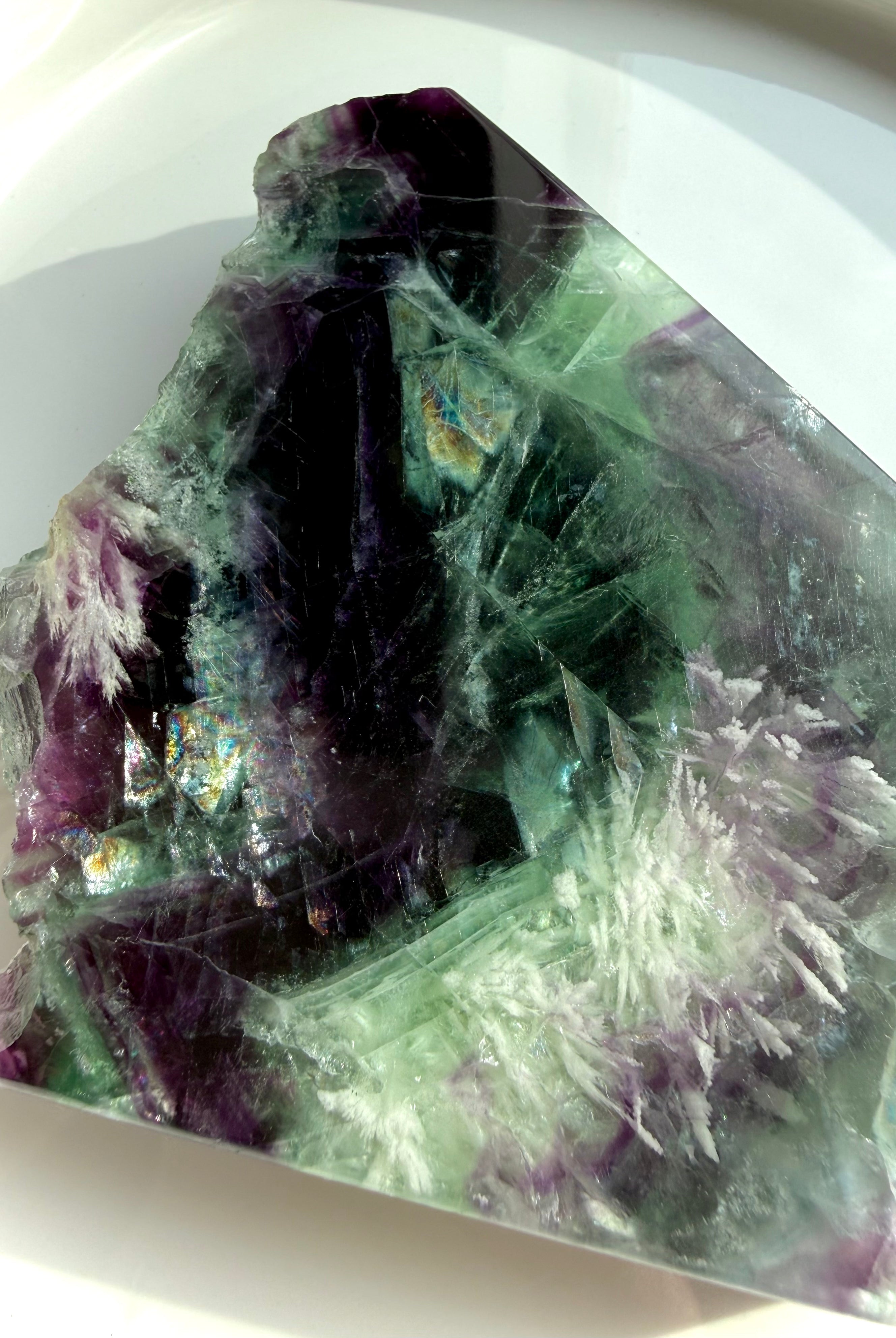 Flatlay of green and purple fluorite slab showing rainbow internal flashes and white scolecite snowflake inclusions