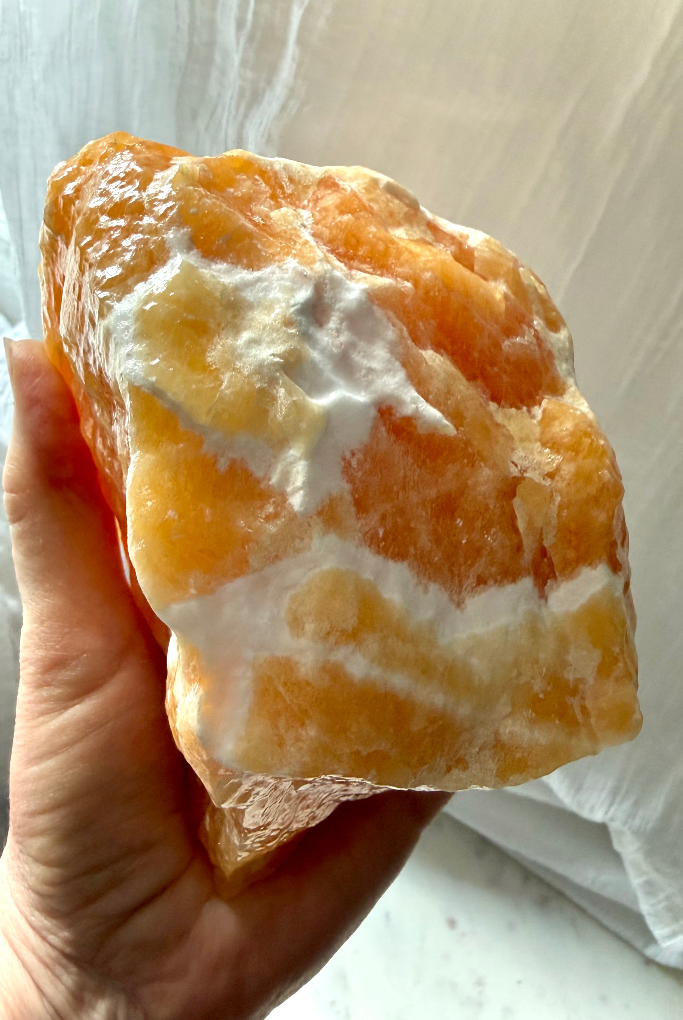 Handheld Orange Calcite statement crystal with creamy white calcite matrix and rich honey-orange color