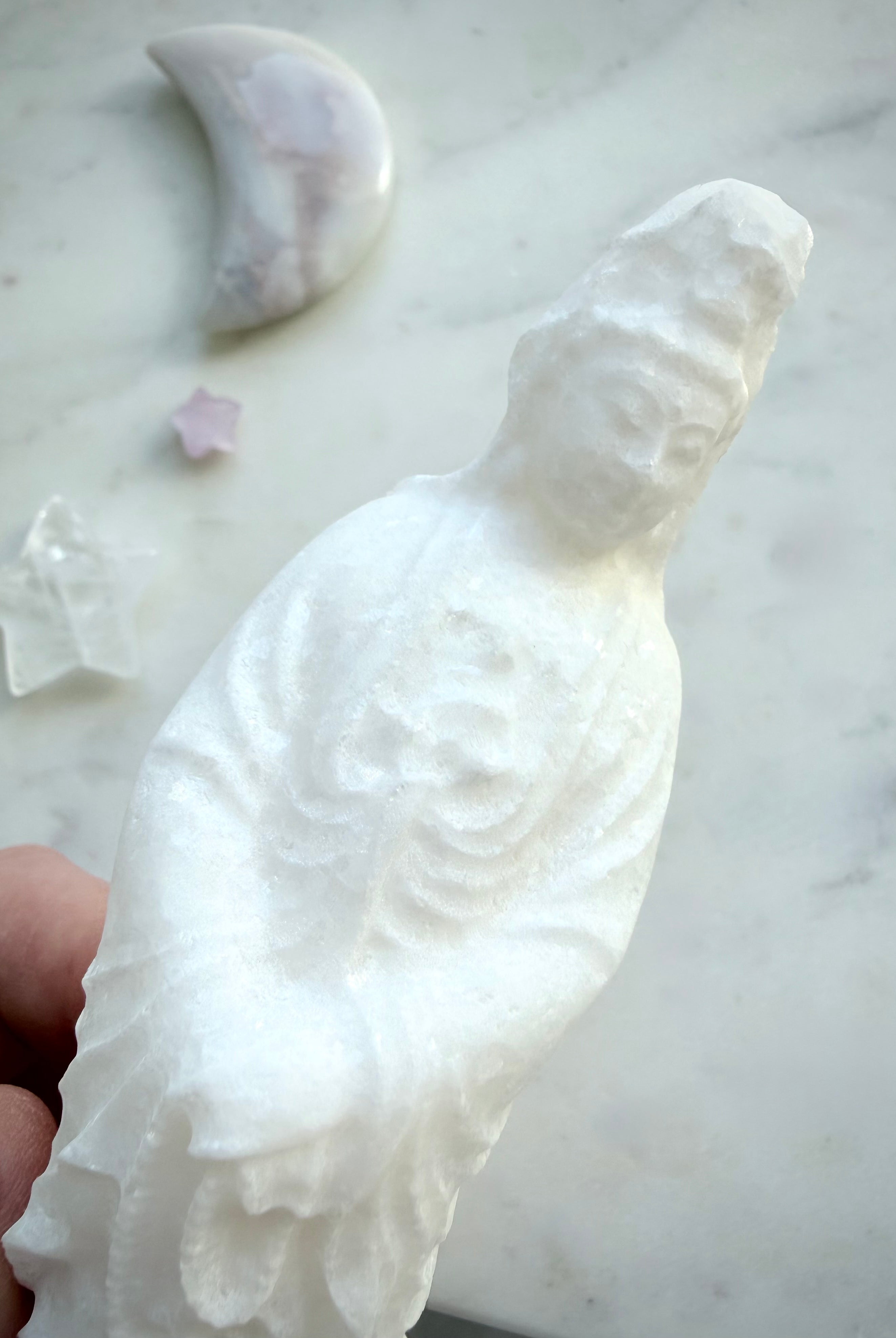 Close-up of White Jade Quan Yin statue showing serene facial features and natural crystalline texture