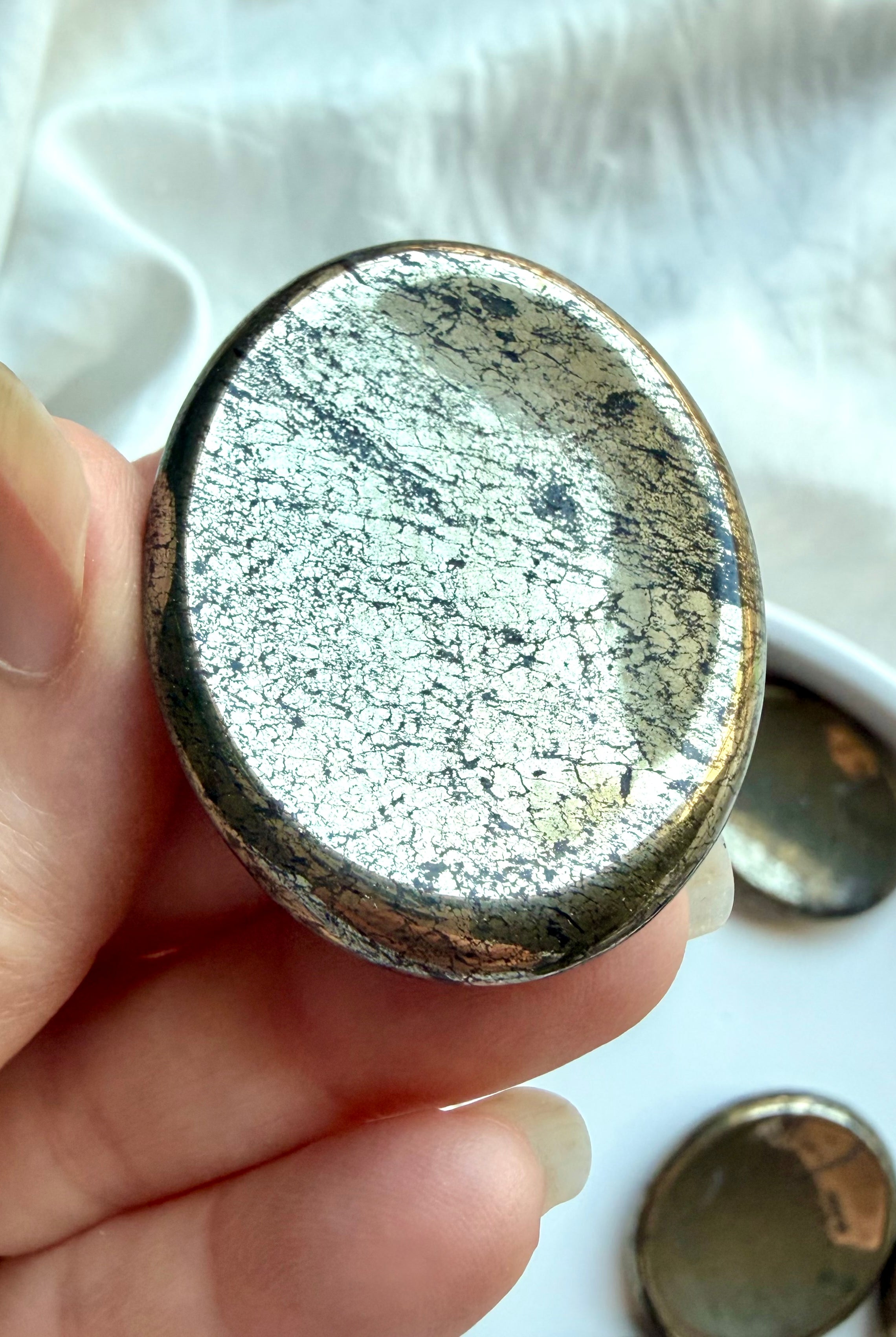 Pyrite worry stone close-up with brilliant reflective luster, crystalline texture and mineral inclusions