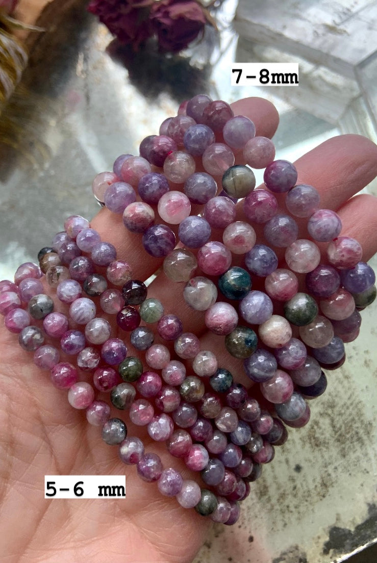 Green Unicorn Stone bracelets — Watermelon Tourmaline in Lepidolite — held over mirror in 5–6mm and 7–8mm bead sizes. Healing crystal jewelry for stress relief + grounding