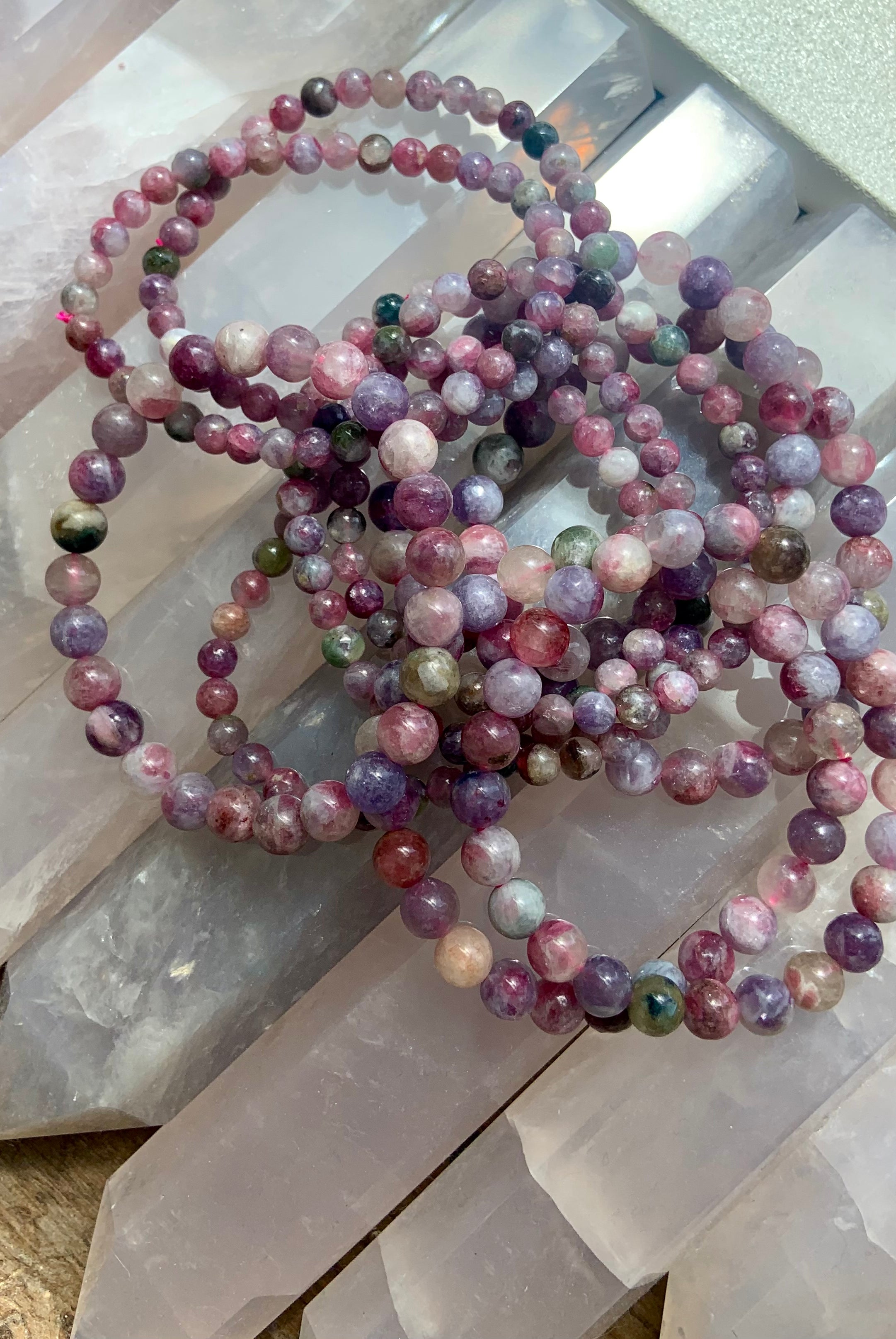 Overhead view of Green Unicorn Stone bracelets — Watermelon Tourmaline in Lepidolite — resting on crystal points. Heart chakra crystal jewelry for peace + emotional healing