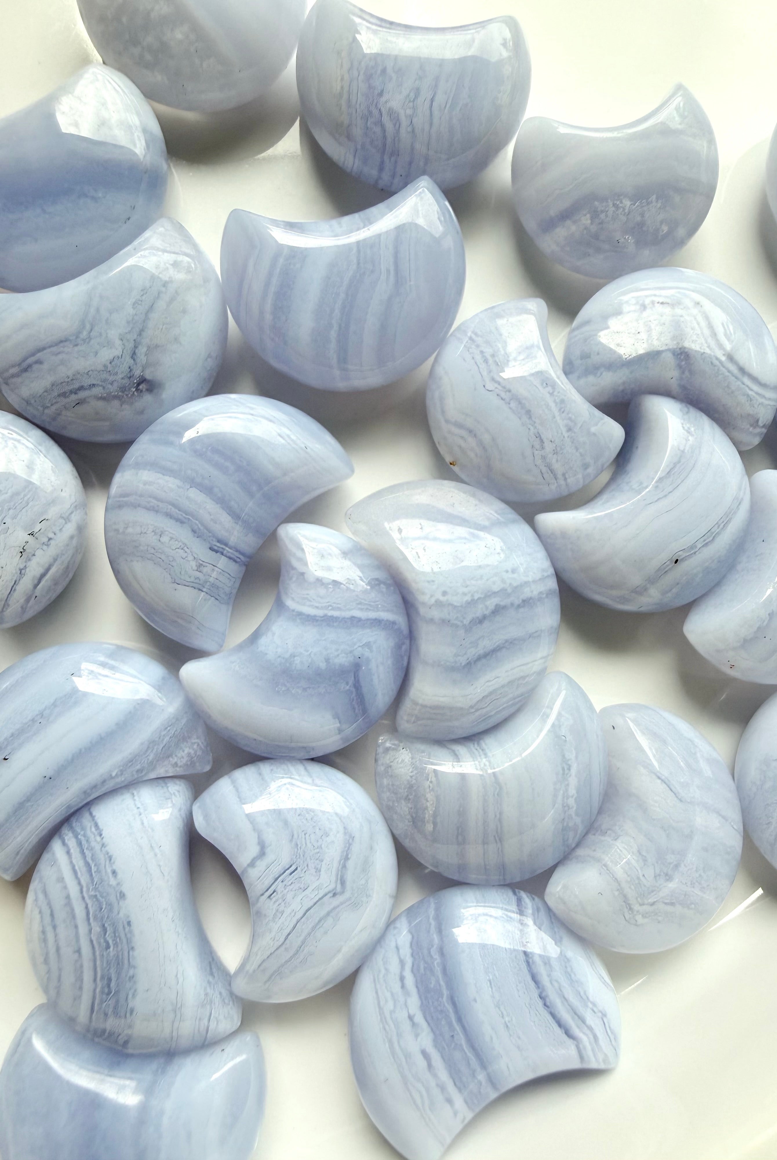 Close-up of polished Blue Lace Agate crescent moon carvings highlighting soft blue color and white lace banding