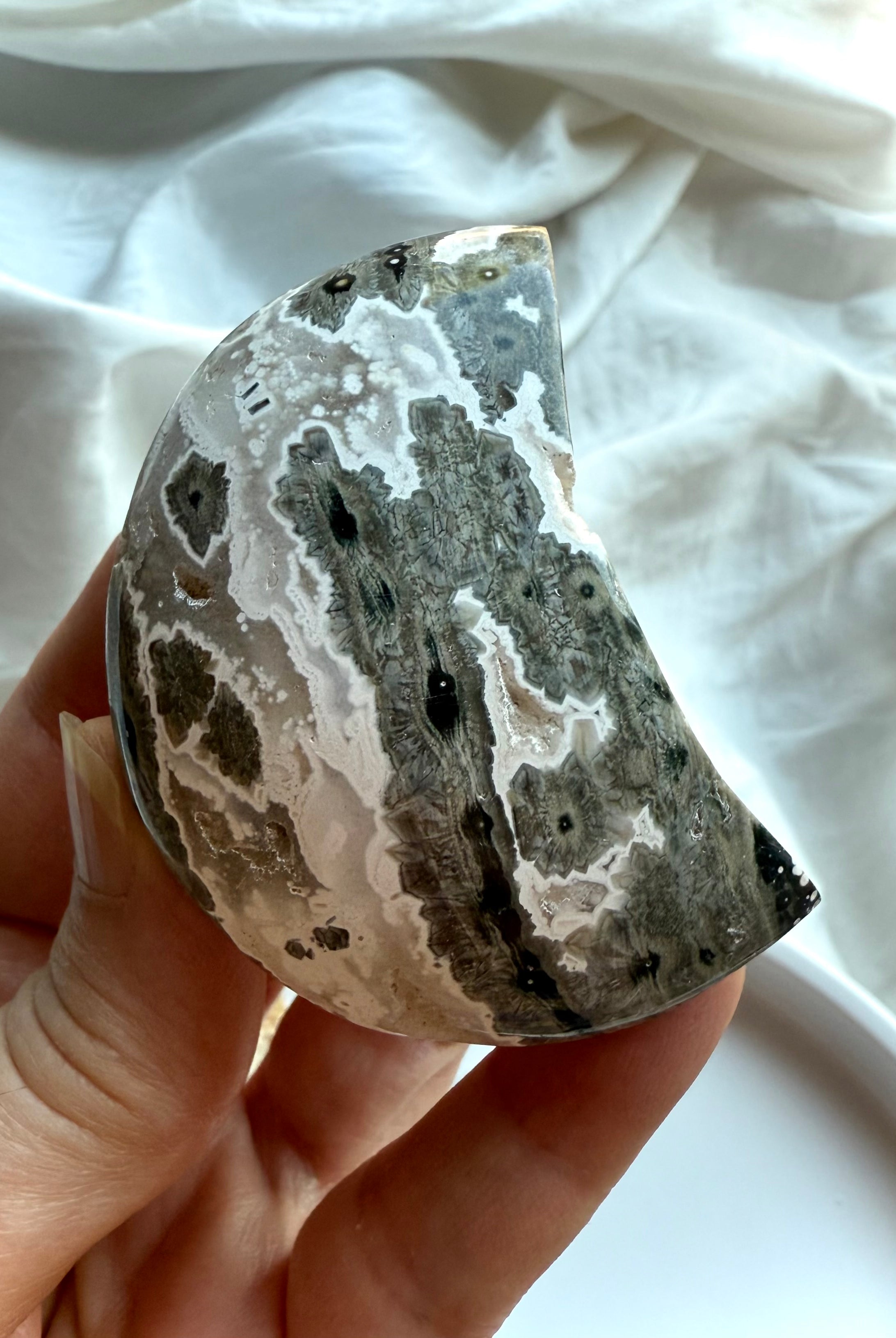Gray Ocean Jasper crescent moon palm stone with striking black and white orbicular details, soothing crystal for inner healing