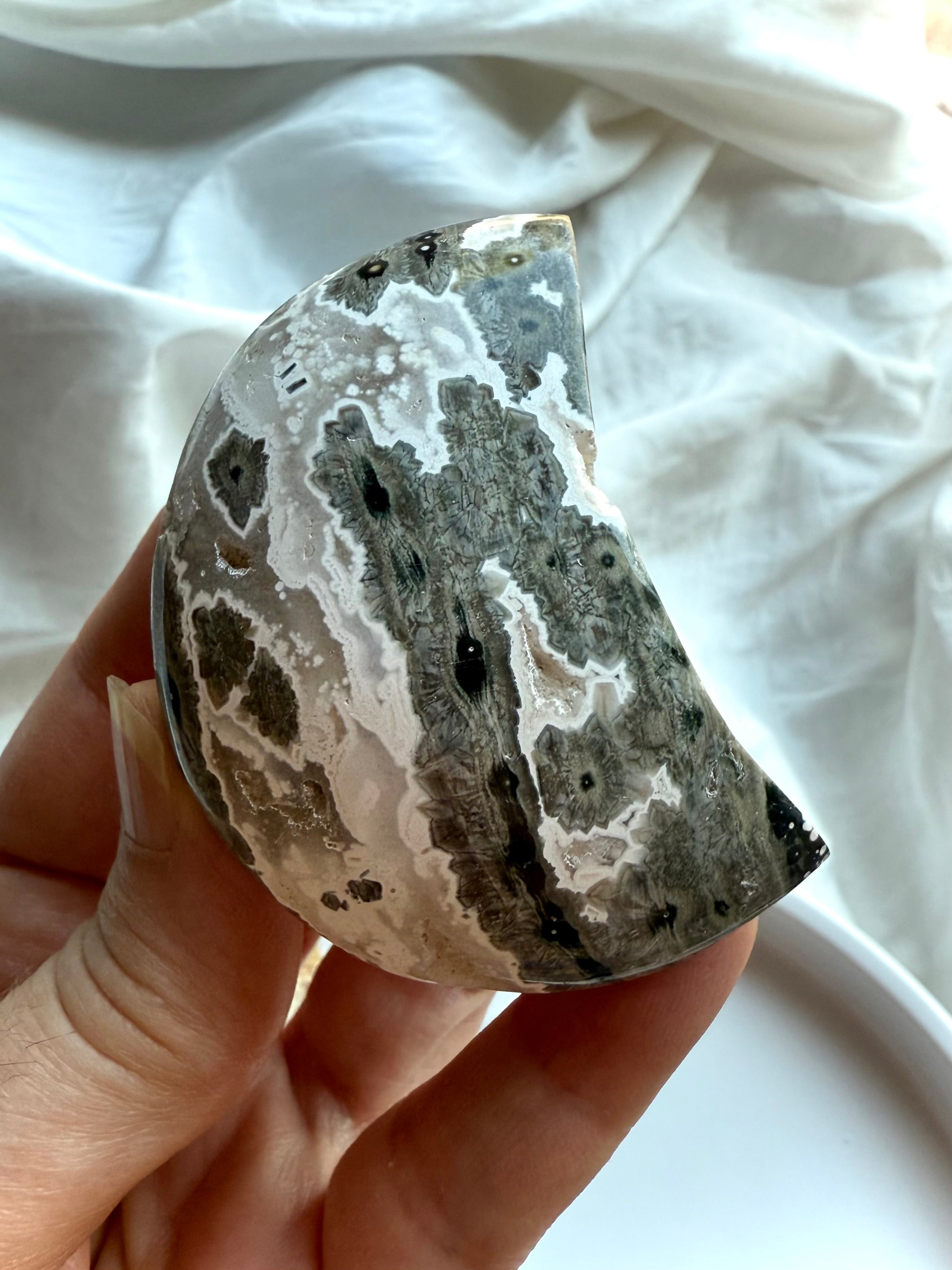 Gray Ocean Jasper crescent moon palm stone with striking black and white orbicular details, soothing crystal for inner healing