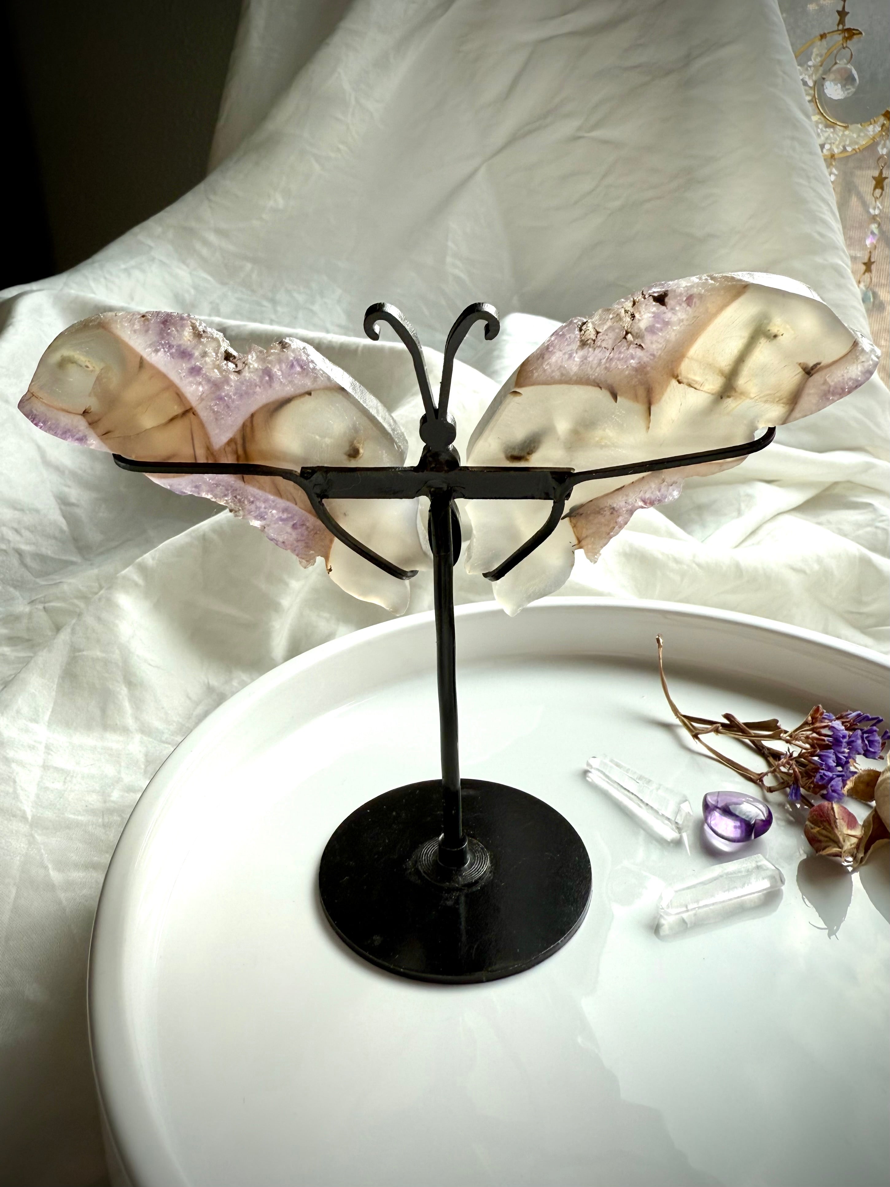 Back view of agate butterfly wings with amethyst druzy texture, mounted on black metal stand for display.