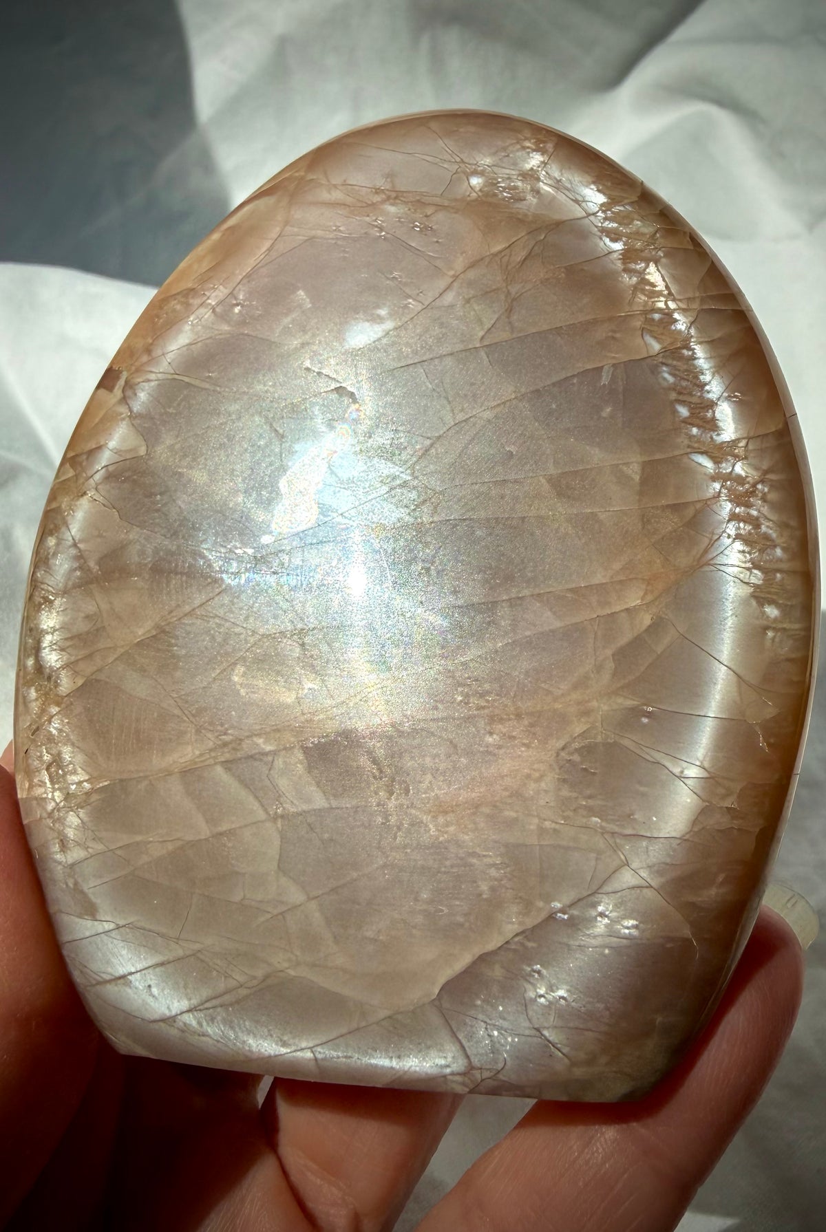 Peach Moonstone freeform held in hand with bright silvery Moonstone shimmer and subtle rainbow flash