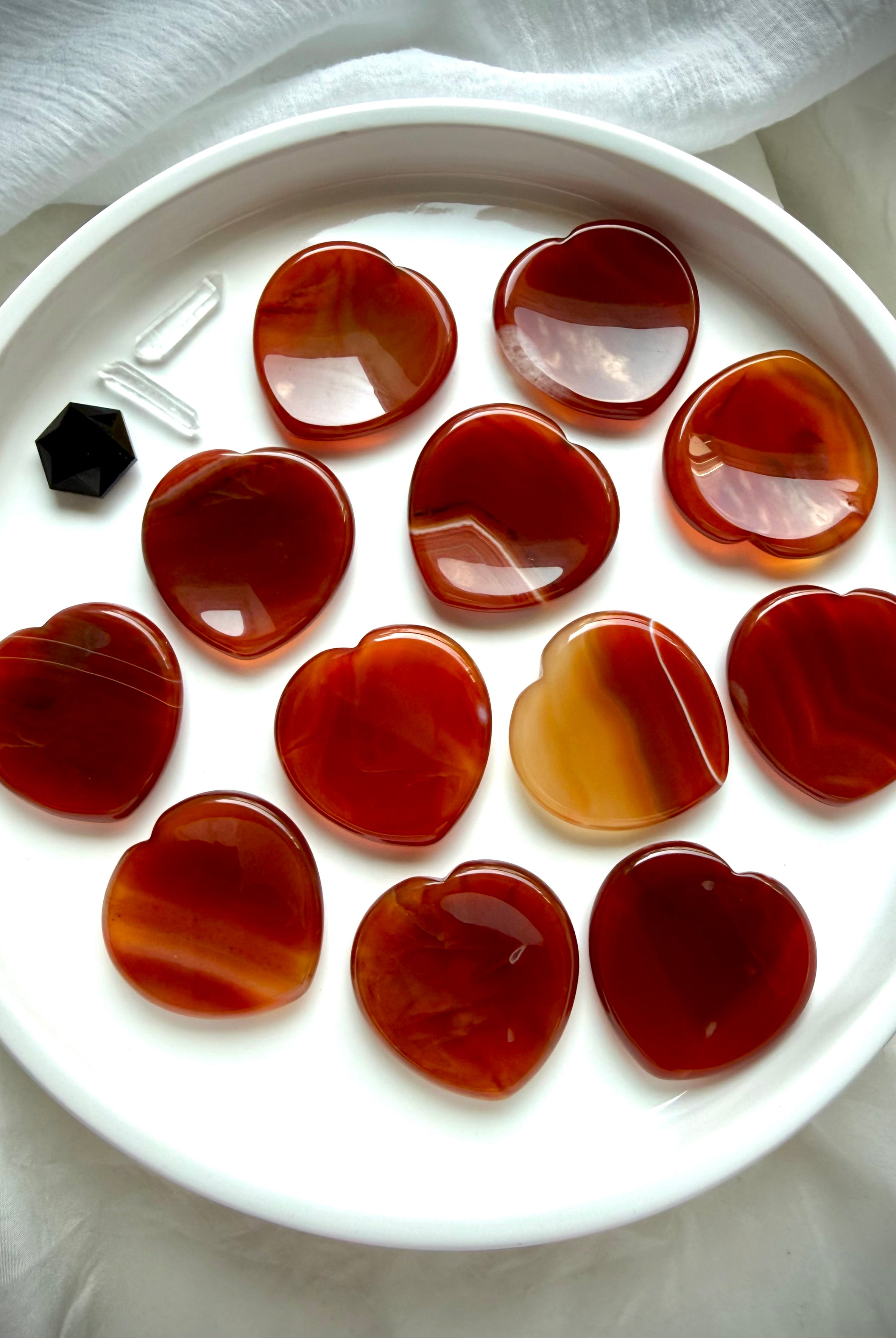 Carnelian heart worry stones on white tray showing natural red, orange, amber and golden color variation