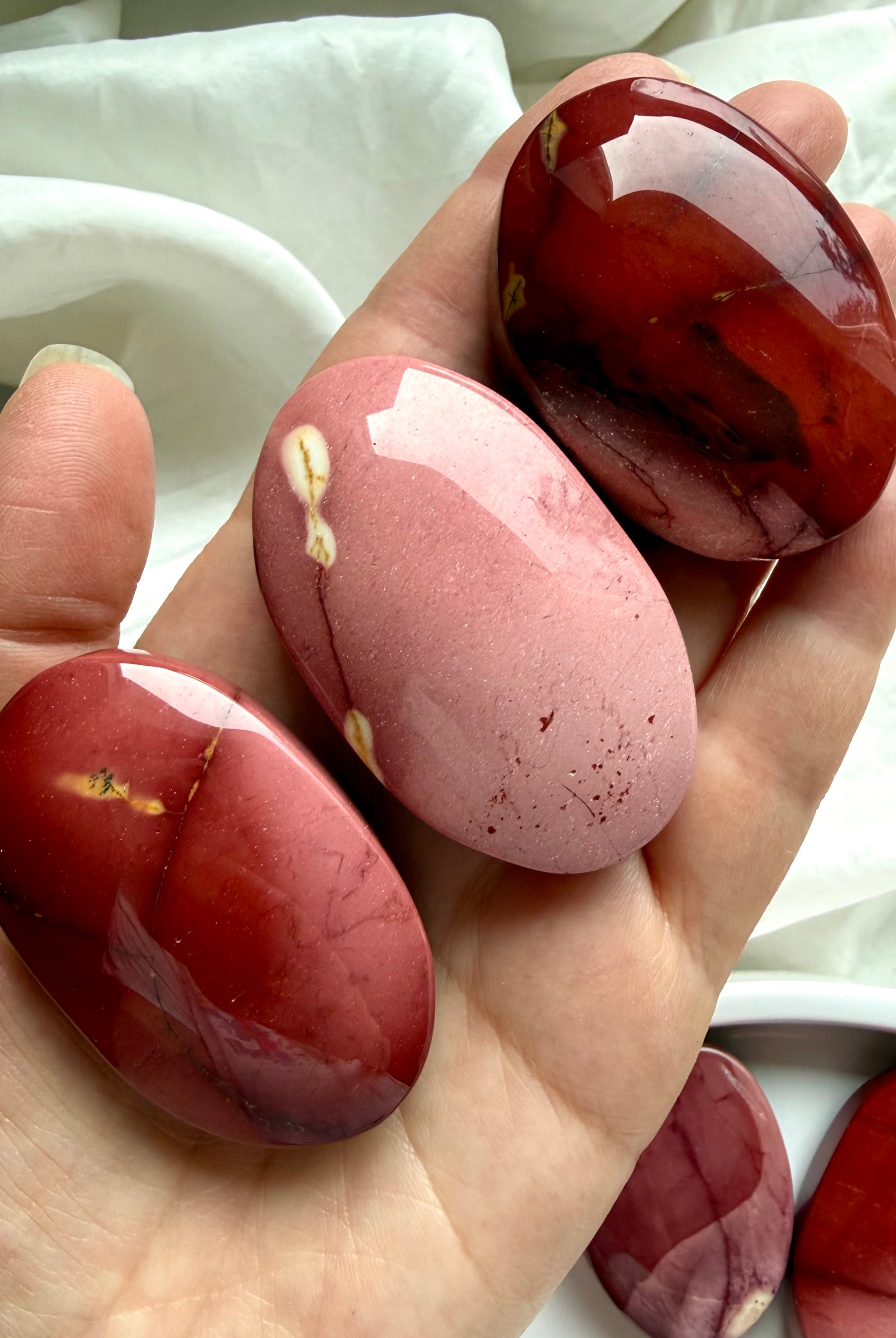 large polished Mookaite Jasper palm stone held in hand with rich earthy tones for grounding and confidence