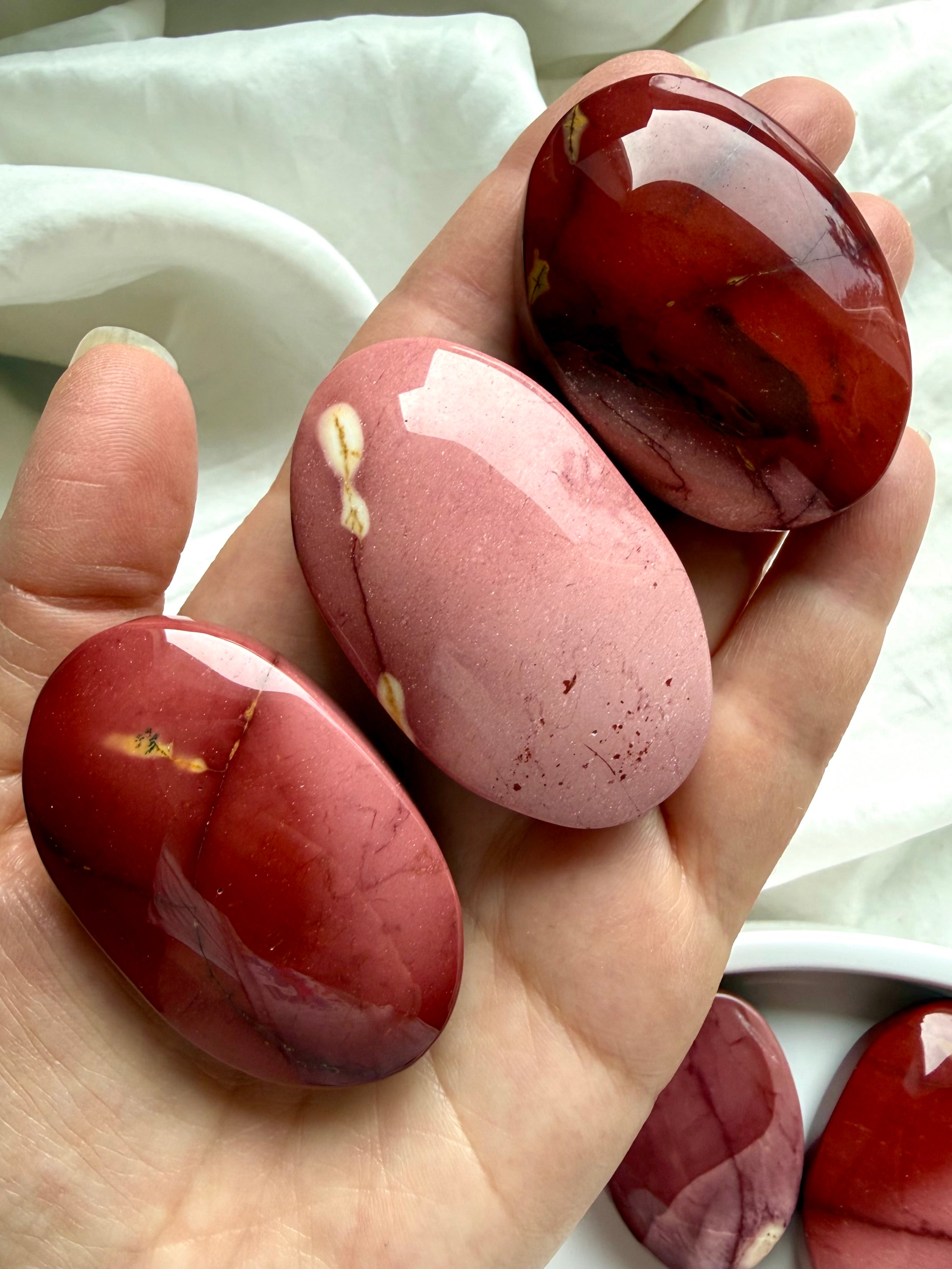 large polished Mookaite Jasper palm stone held in hand with rich earthy tones for grounding and confidence