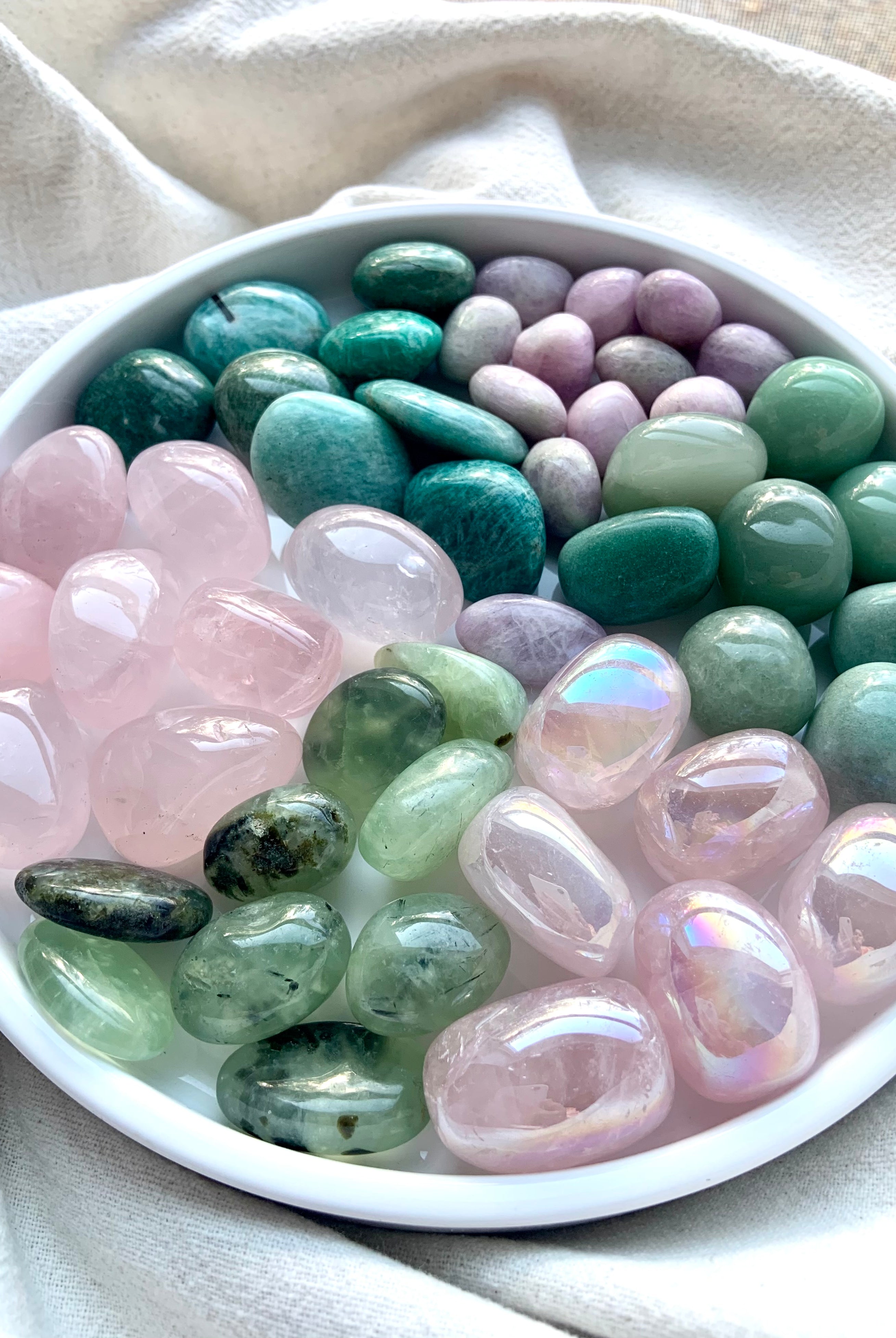 Wide-angle view of Heart Chakra crystal healing set with grouped pink and green tumbles arranged on a white plate to show color variety and quality.