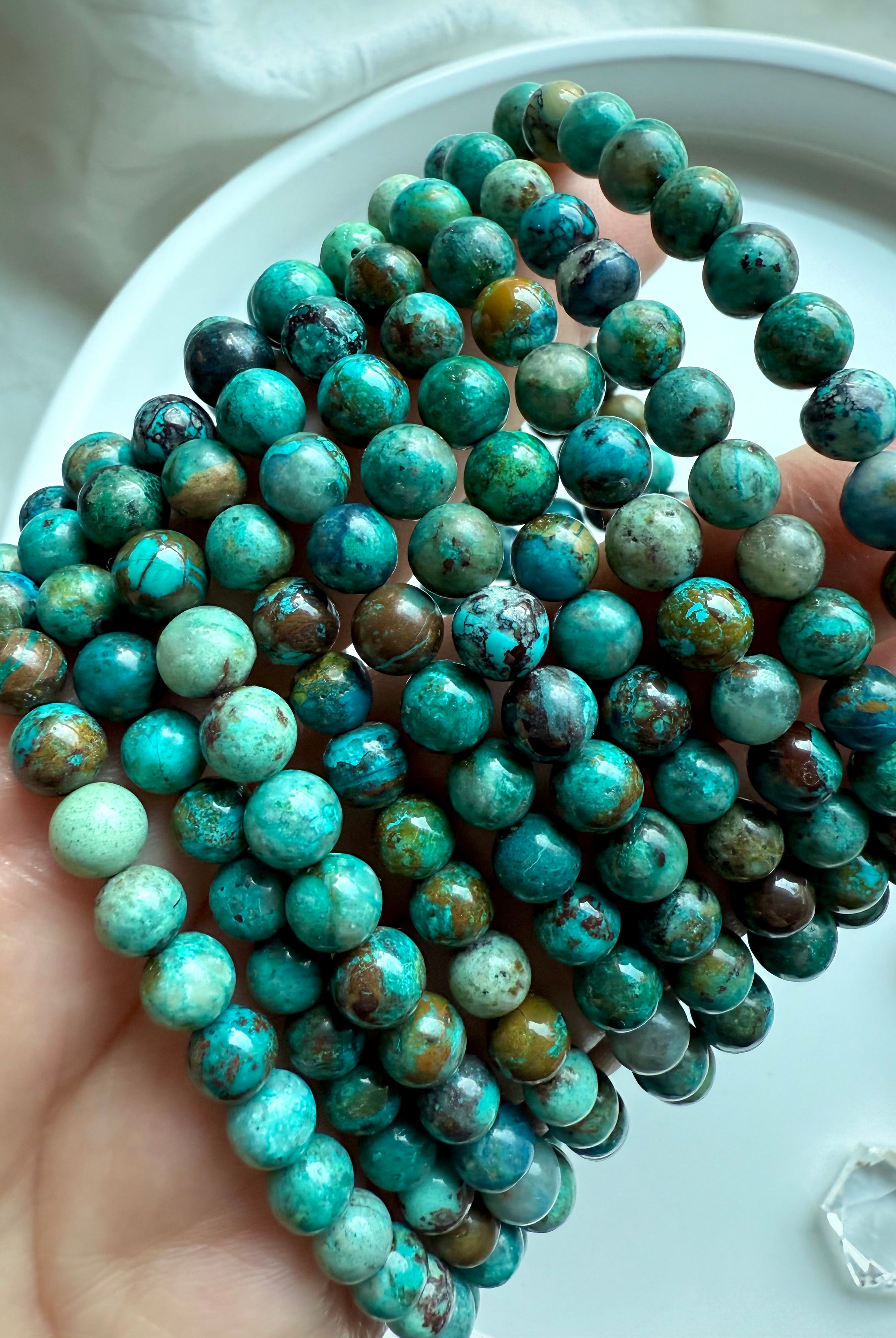 Earthy Chrysocolla Shattuckite gemstone bracelets displayed in hand, crystal healing jewelry for empowerment and expression