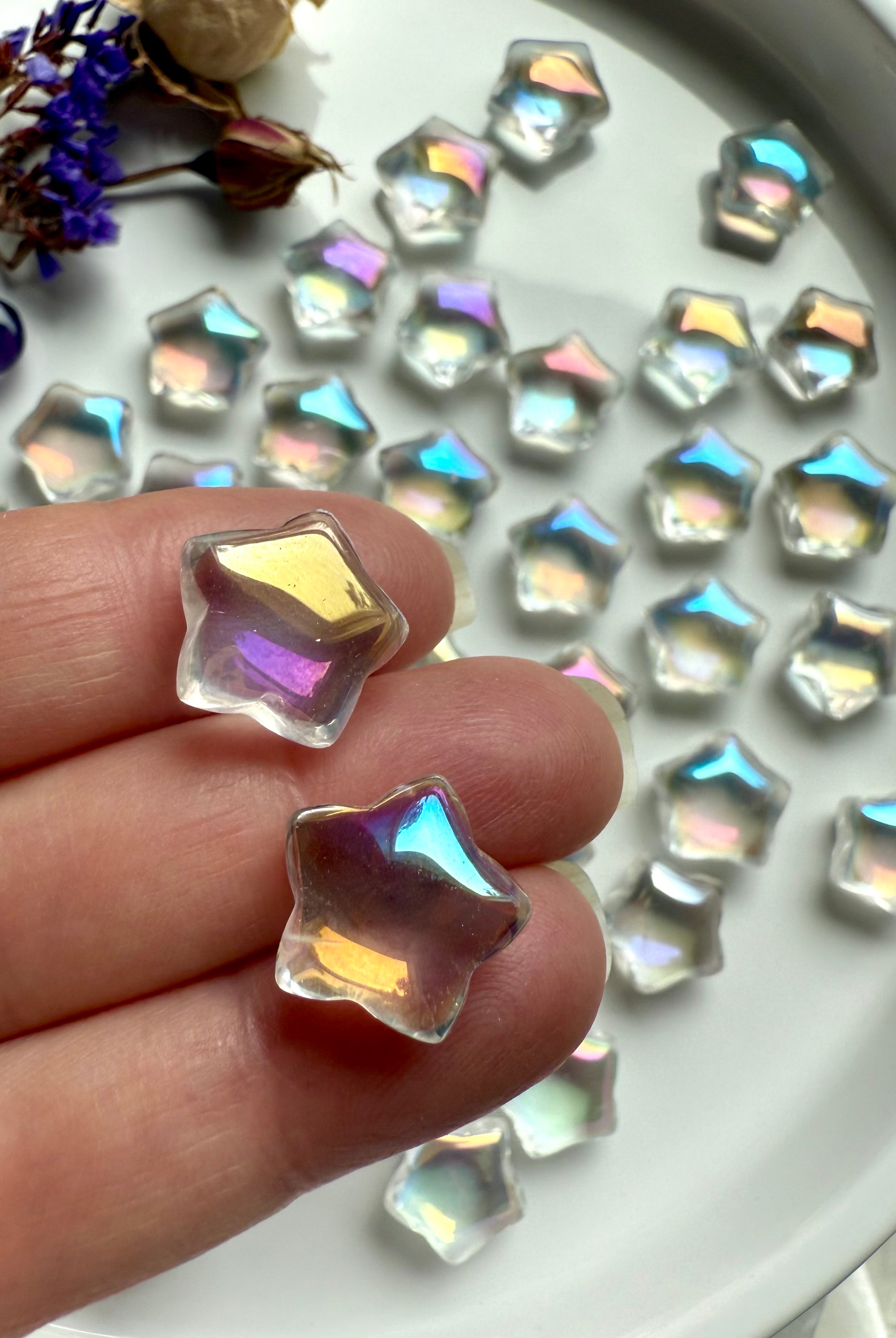 Close-up of mini aura quartz star carvings with opalescent rainbow light — pocket-sized crystals for healing, peace, and meditation