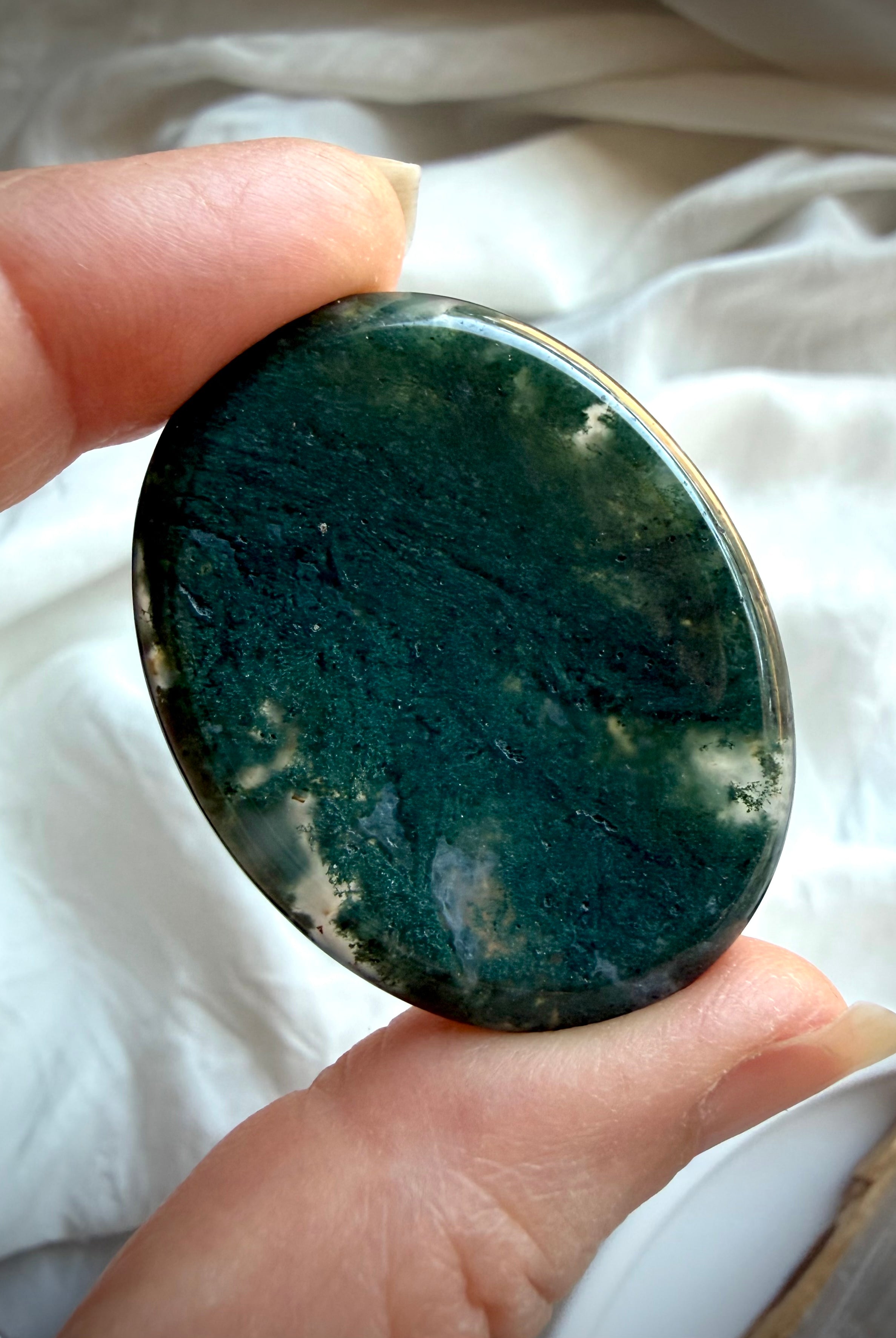 Moss Agate oval worry stone held in hand with dense forest green dendritic inclusions
