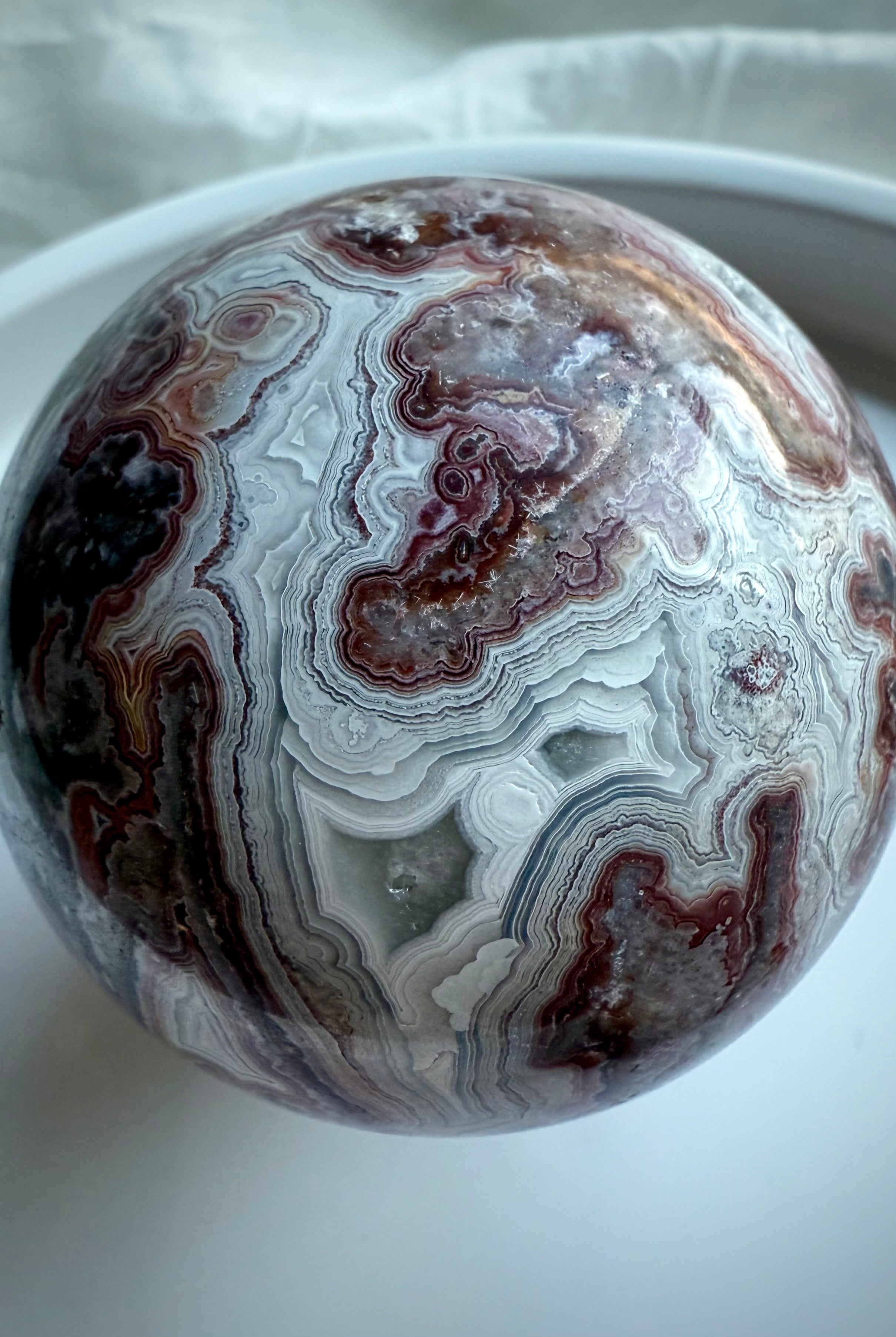 Crazy Lace Agate sphere with druzy window and complex red, white, and gray banding for energetic stability